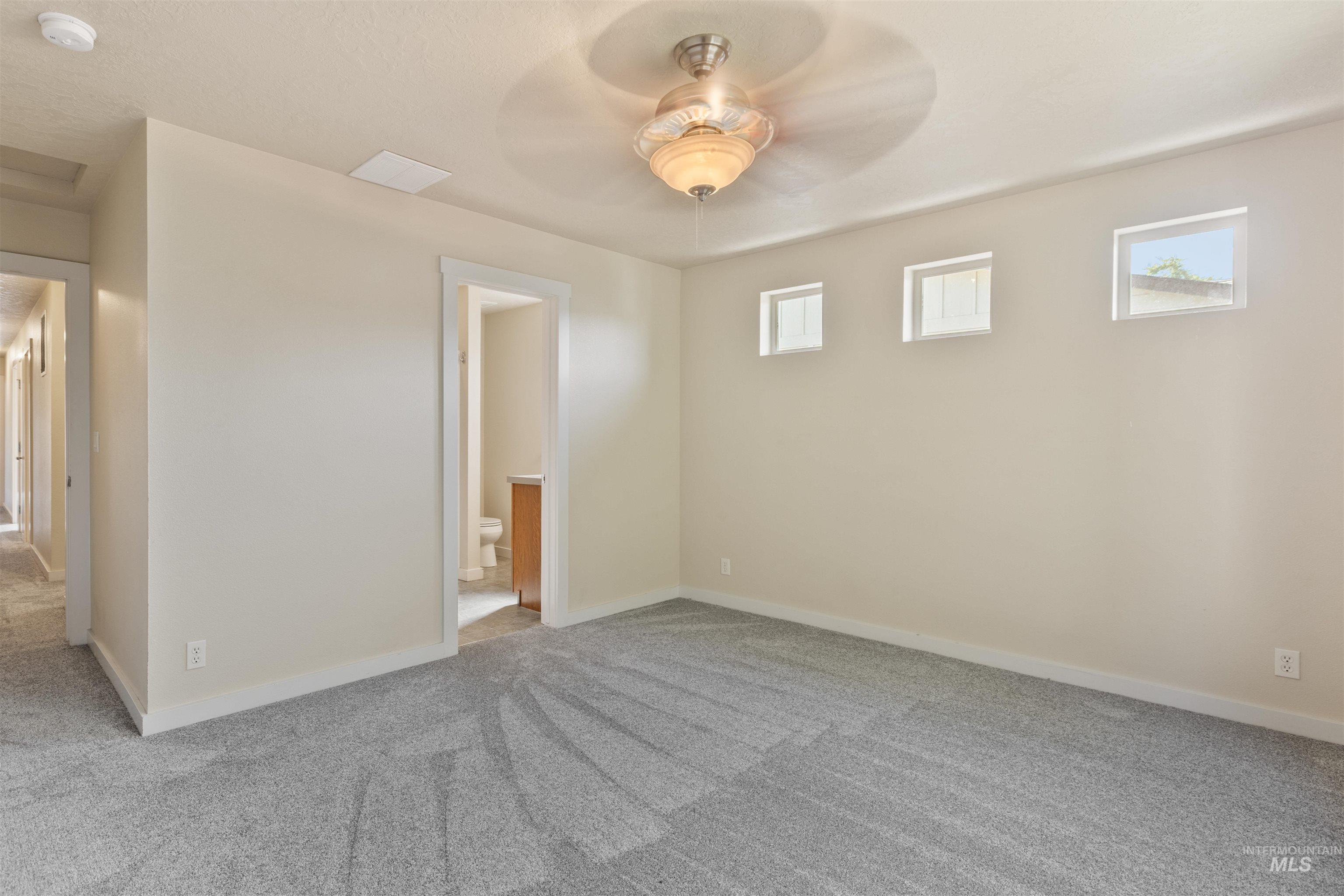 Carpeted spare room featuring baseboards and a ceiling fan
