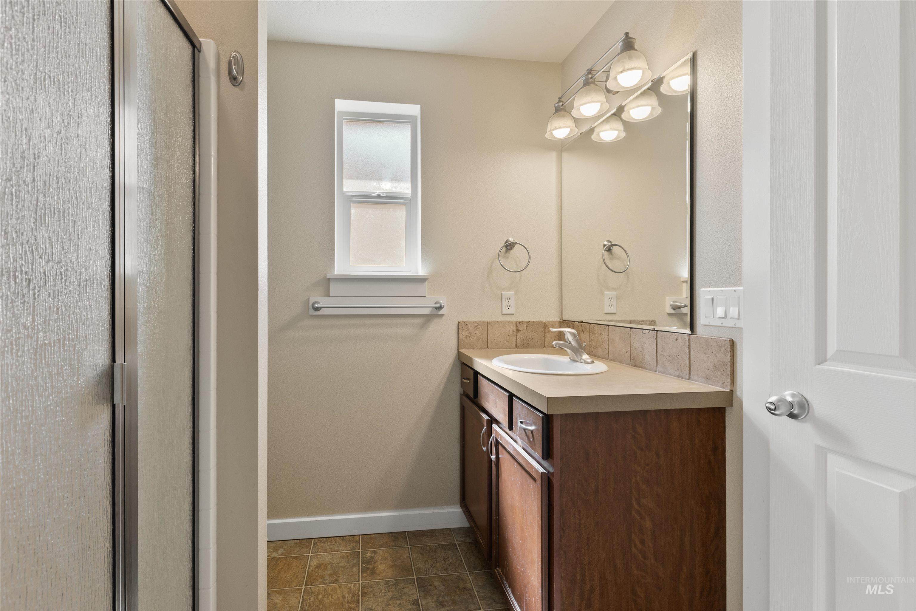 Bathroom with vanity, a stall shower, and dark tile patterned floors