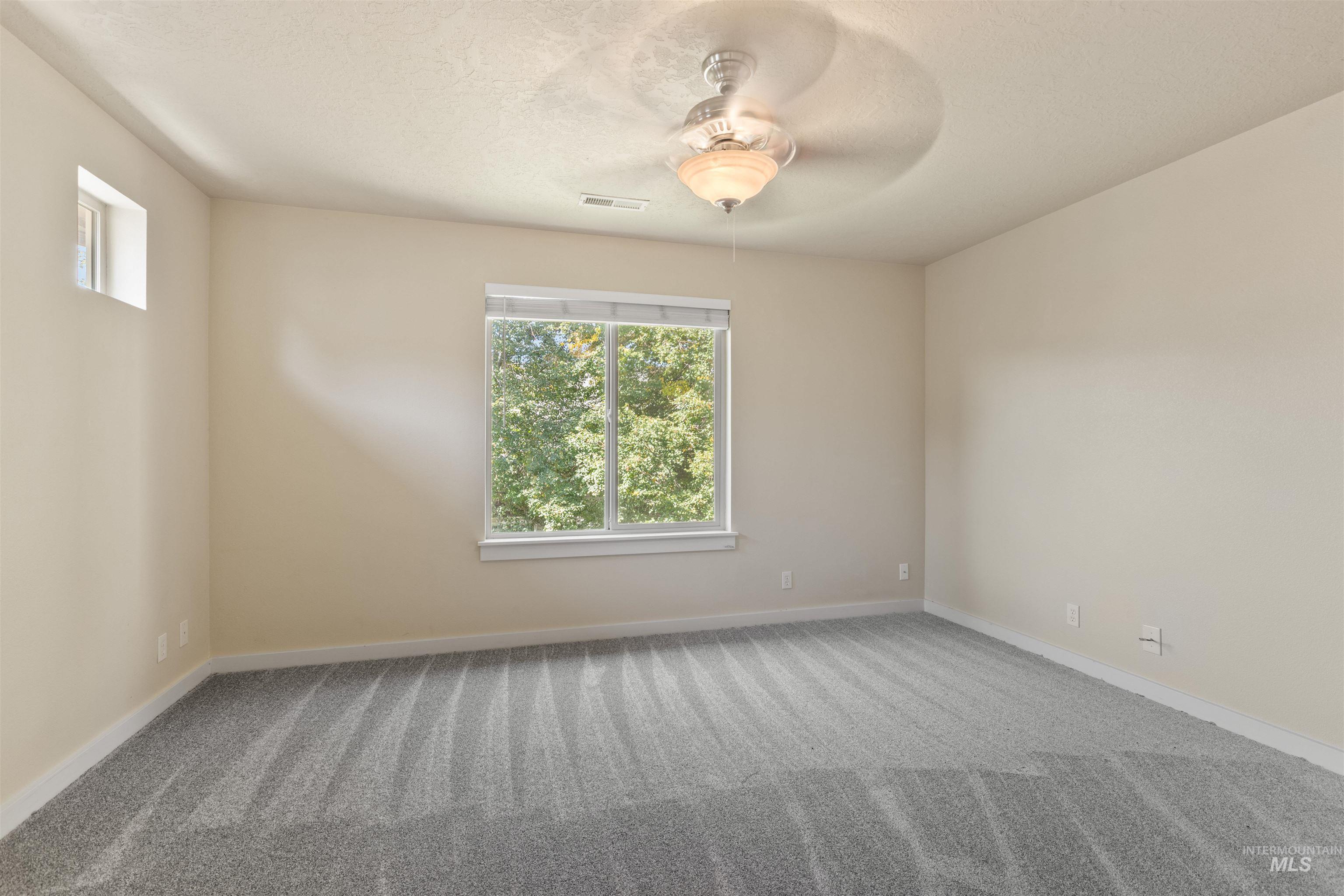 Carpeted spare room featuring ceiling fan and a textured ceiling
