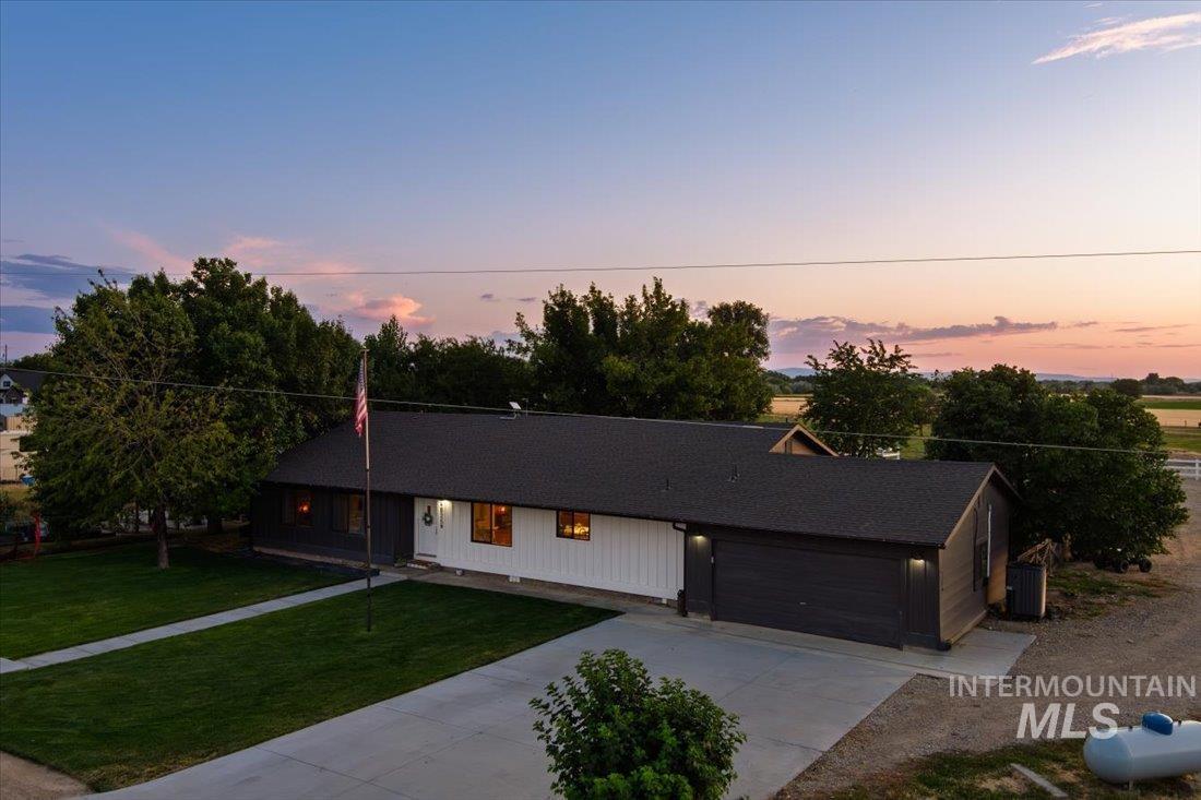 Ranch-style house featuring a yard, driveway, covered porch, and a garage