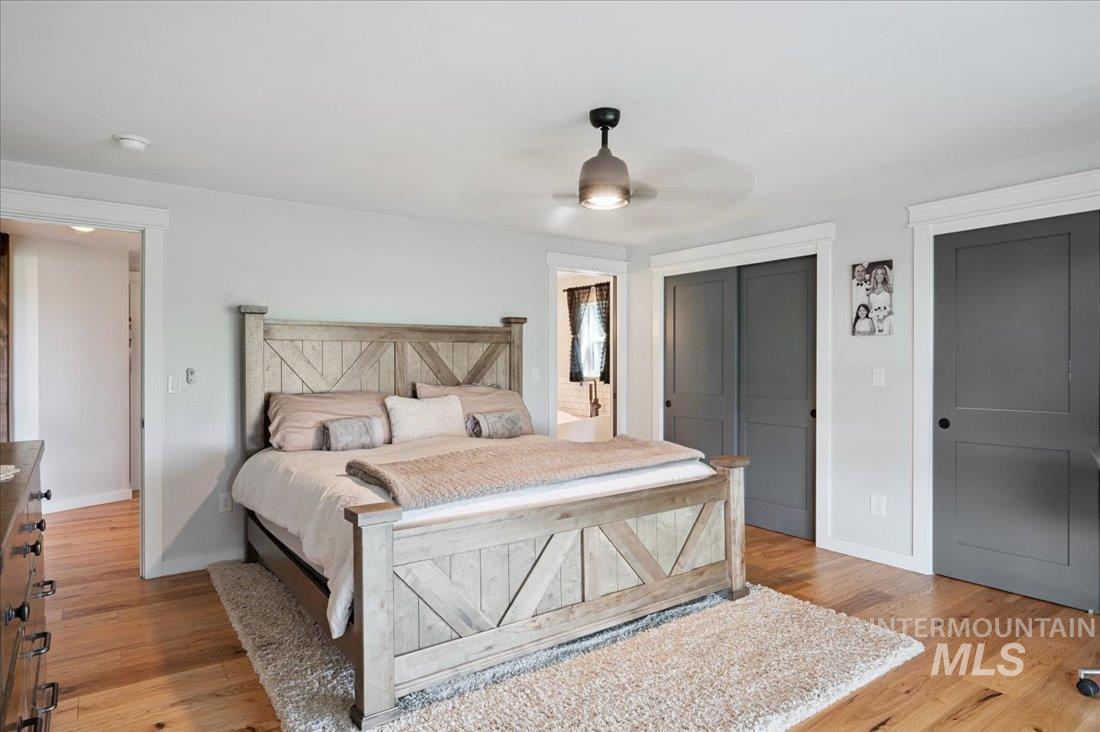 Bedroom featuring multiple closets, light wood-type flooring, and a ceiling fan