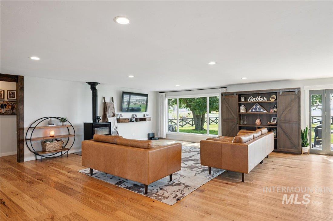 Living room with light wood-style flooring, plenty of natural light, recessed lighting, and a wood stove