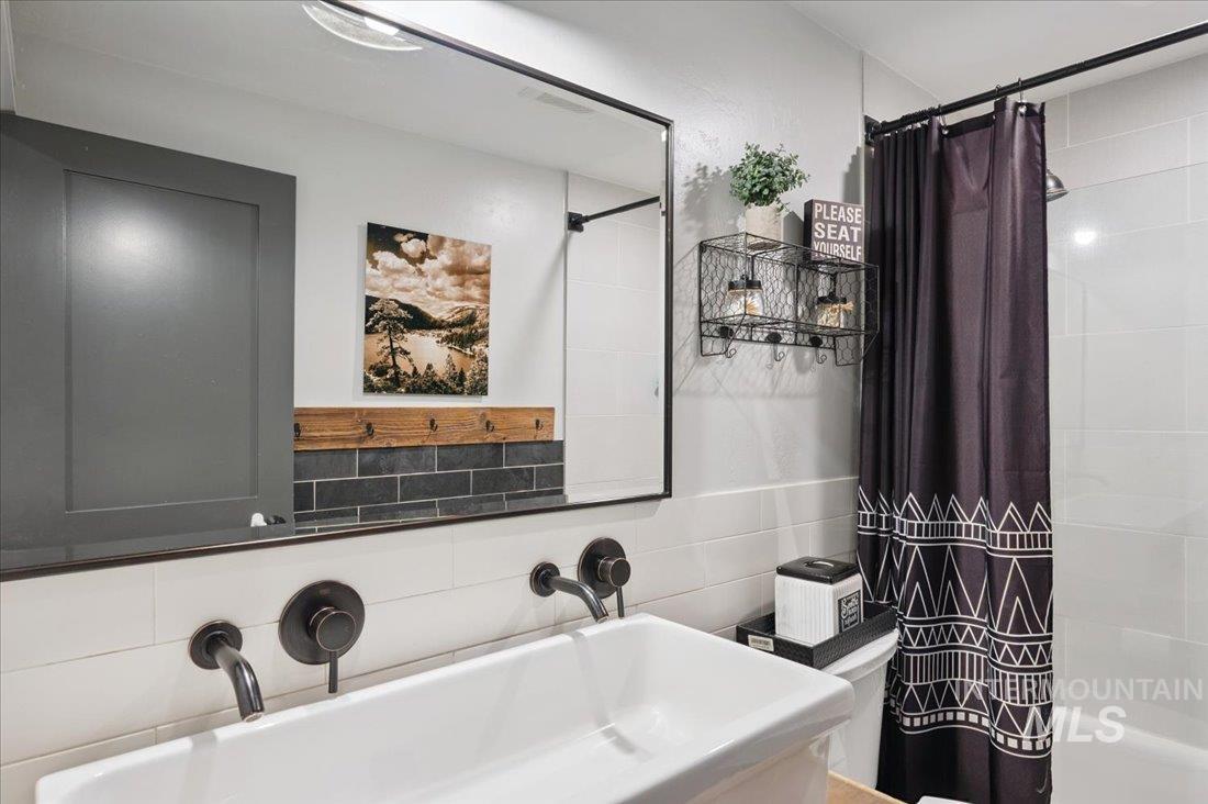 Bathroom featuring backsplash and shower / bathtub combination with curtain