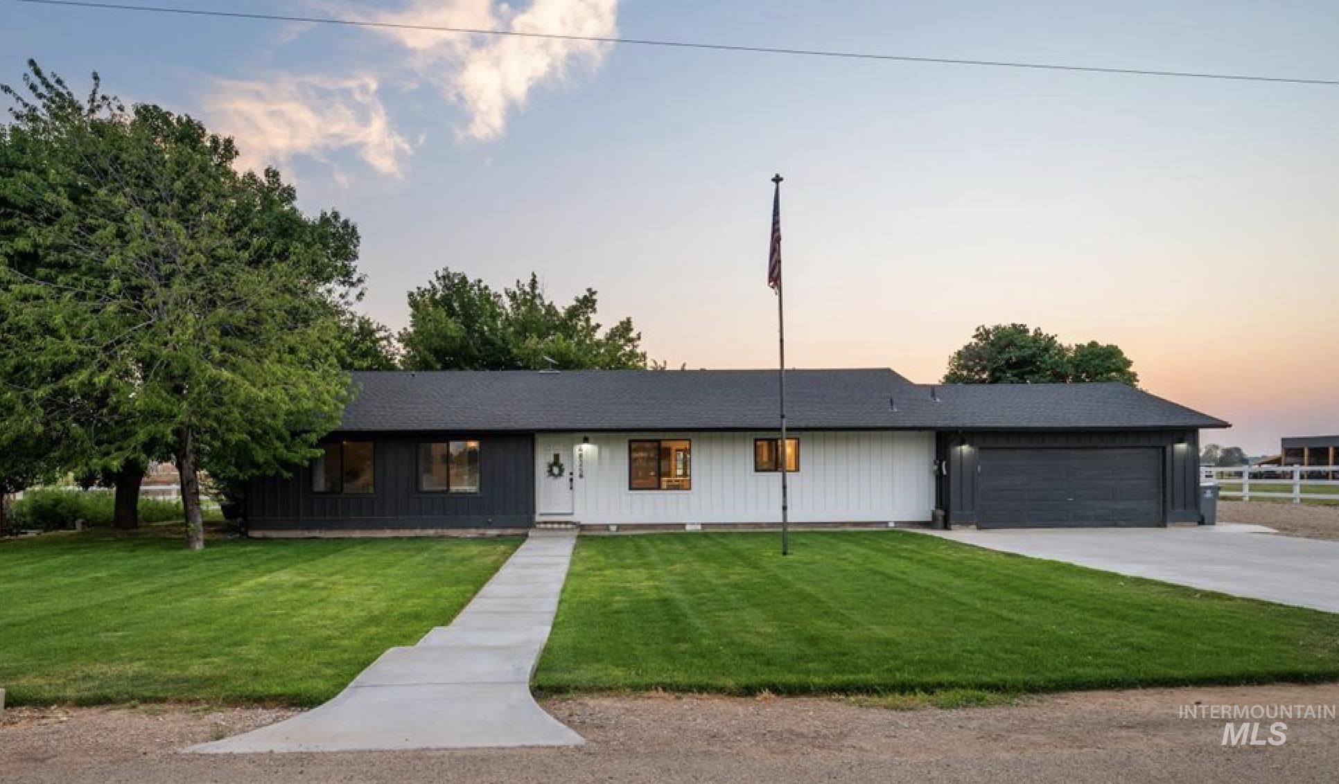 Ranch-style house featuring a garage, a front lawn, and driveway