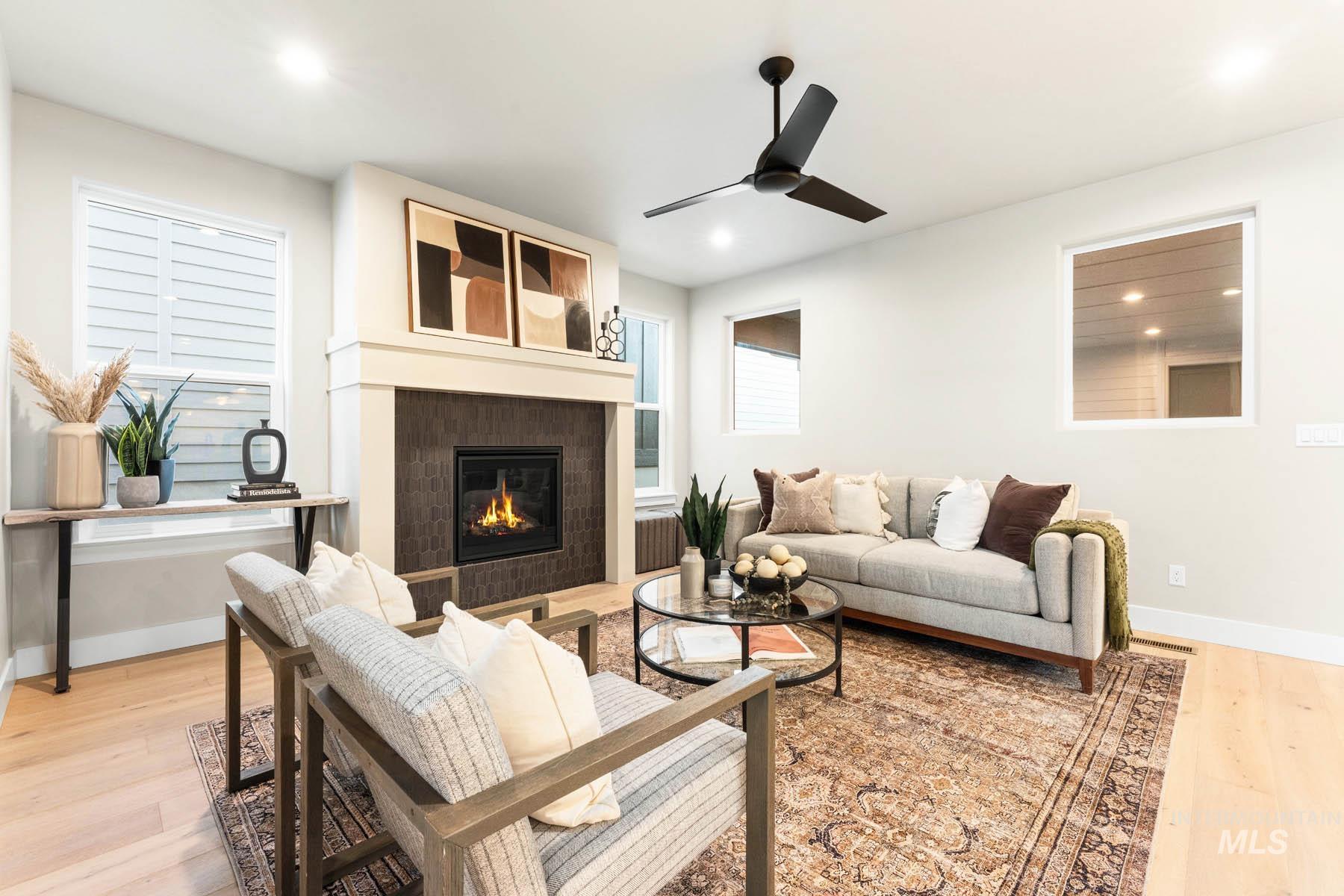 Living area with light wood-style floors, a fireplace, a ceiling fan, and recessed lighting