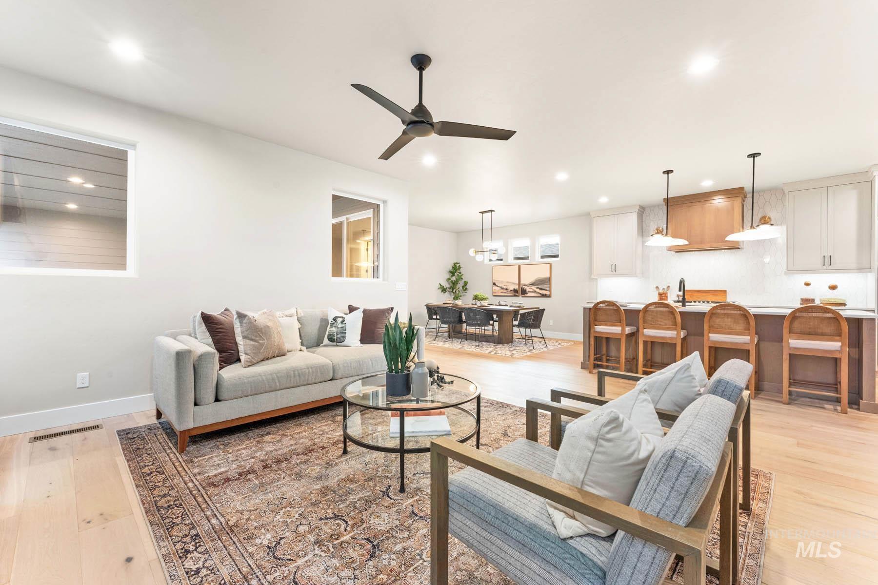 Living area with light wood-style floors, a ceiling fan, and hanging lights