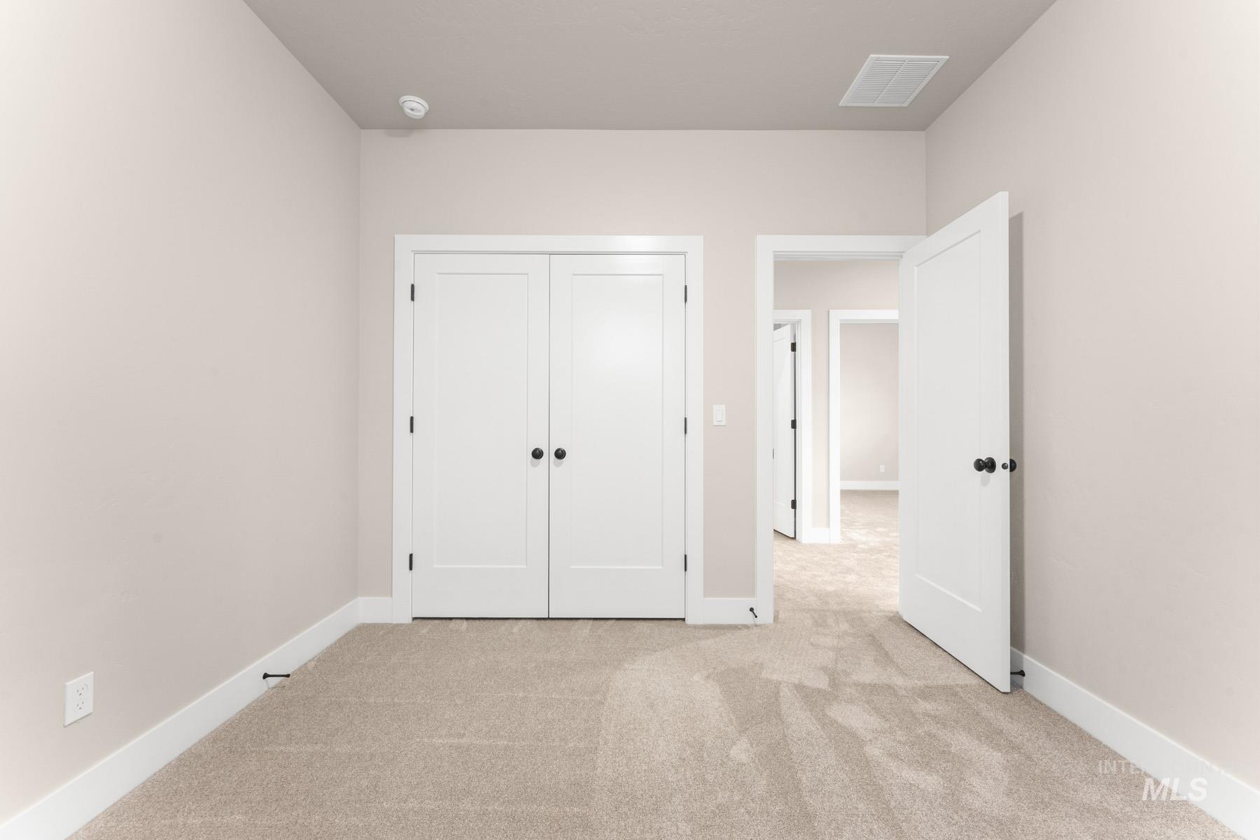 Unfurnished bedroom with light carpet and a closet
