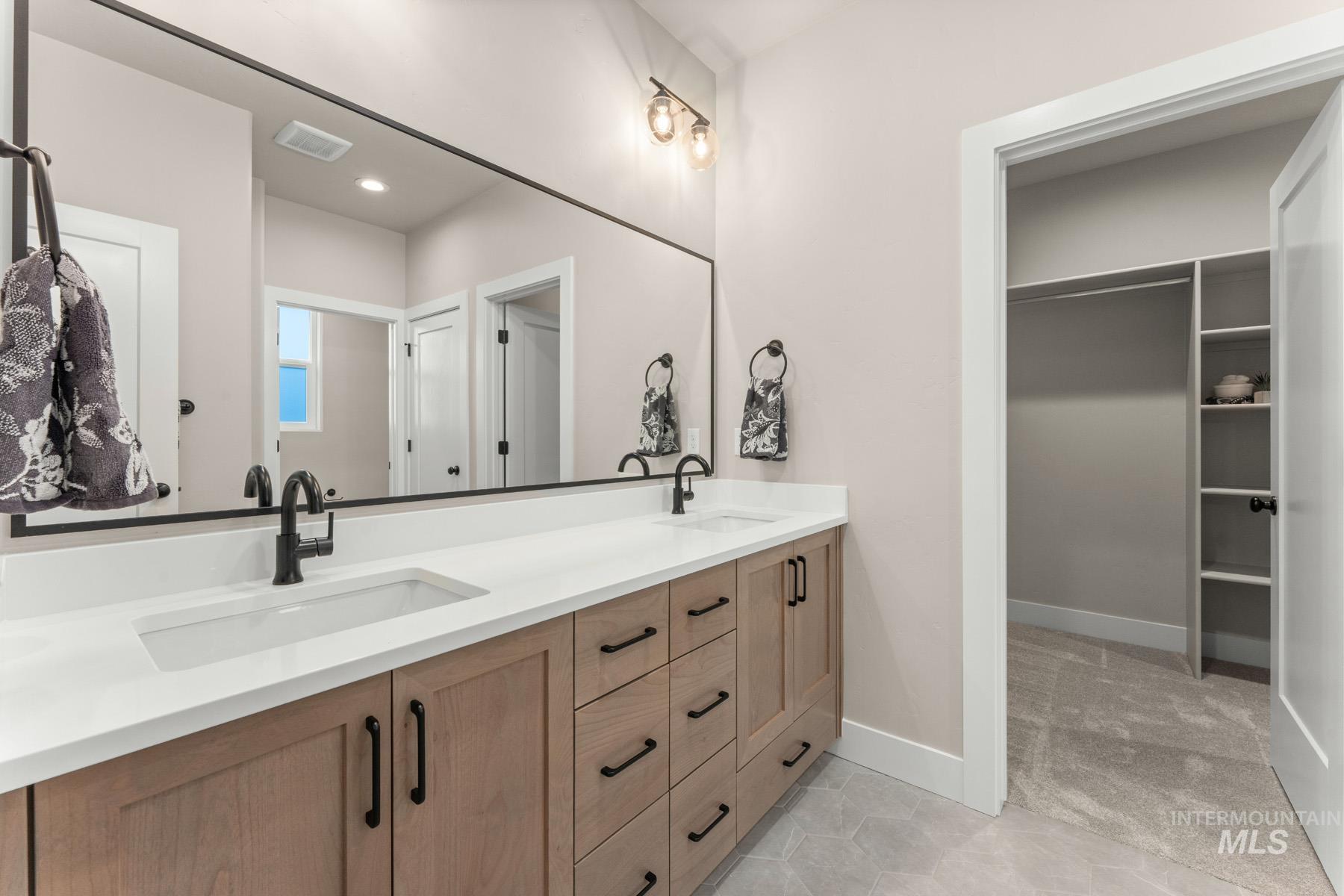 Bathroom featuring double vanity and a spacious closet
