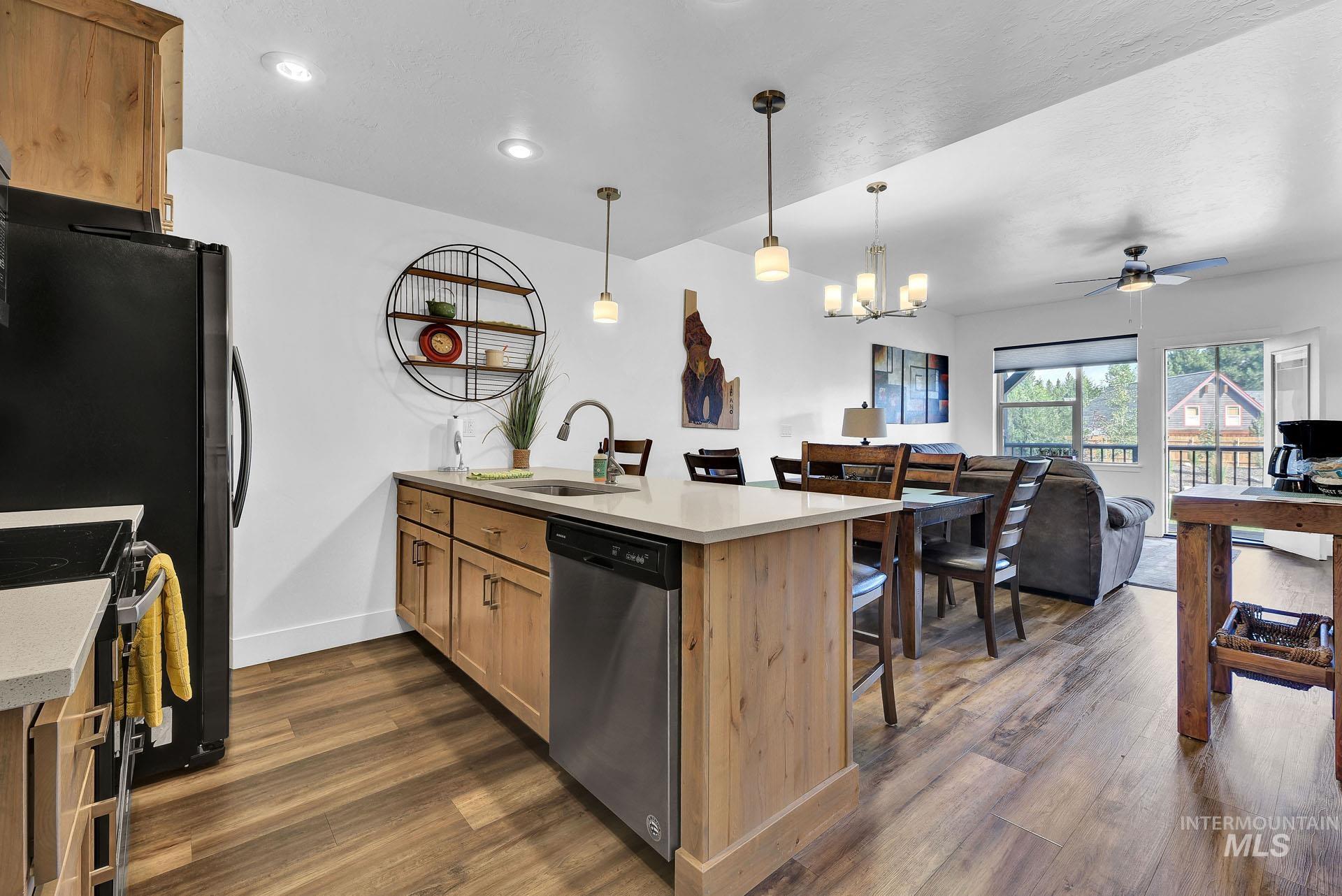 Kitchen with a kitchen breakfast bar, dark wood-style flooring, dishwasher, and open floor plan
