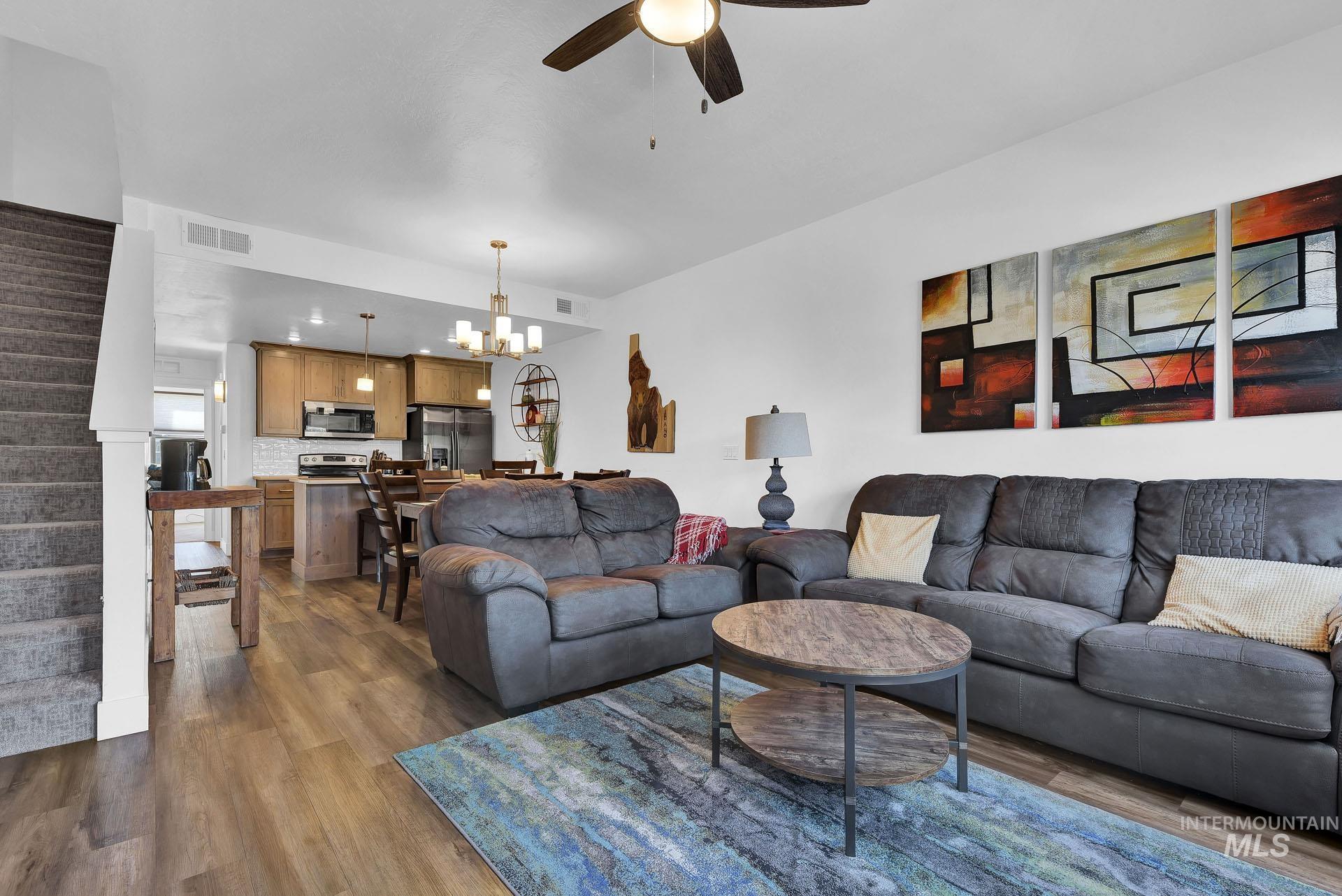 Living room with ceiling fan, dark wood-style floors, and hanging lights