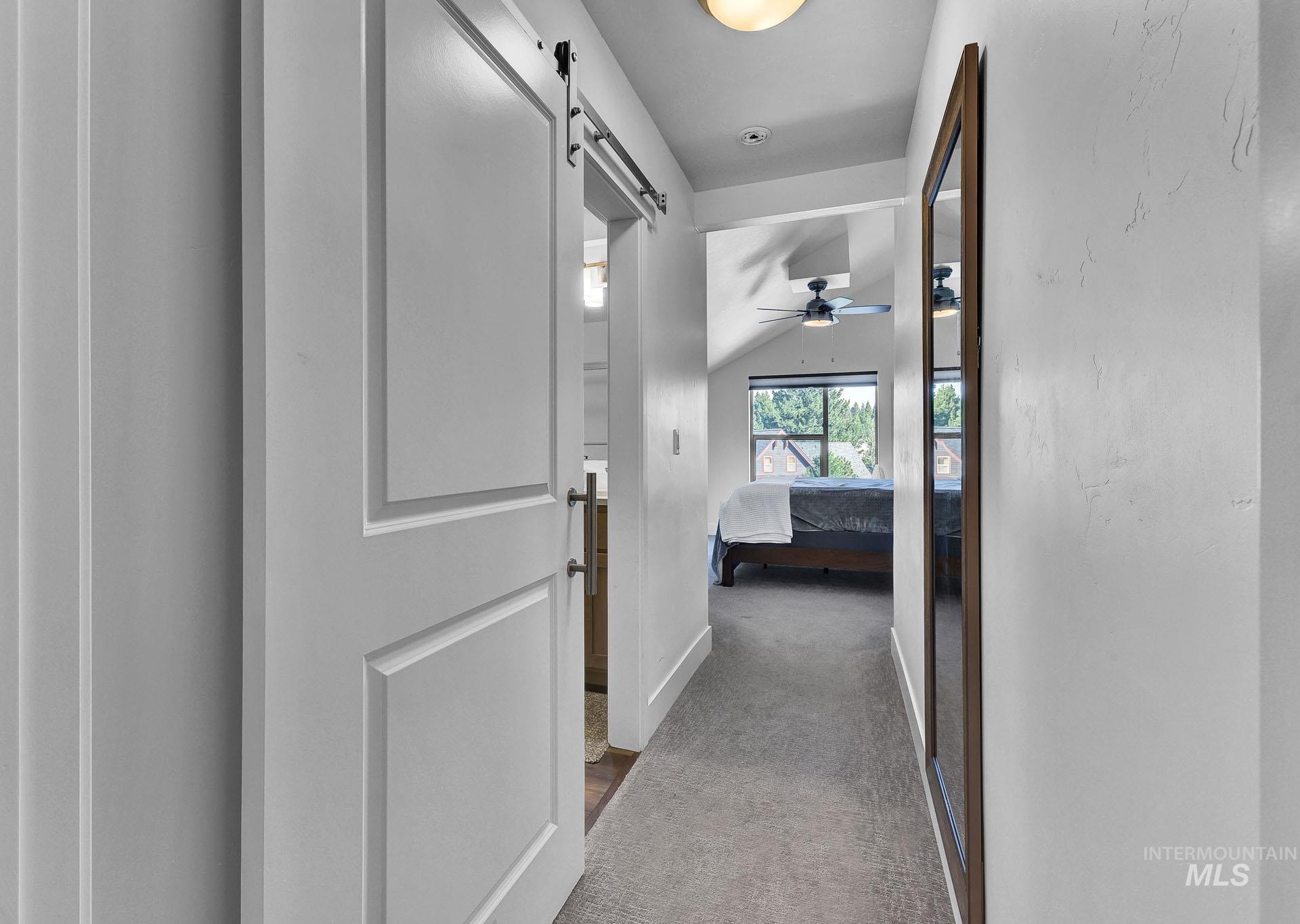 Hallway with lofted ceiling, light colored carpet, and a barn door