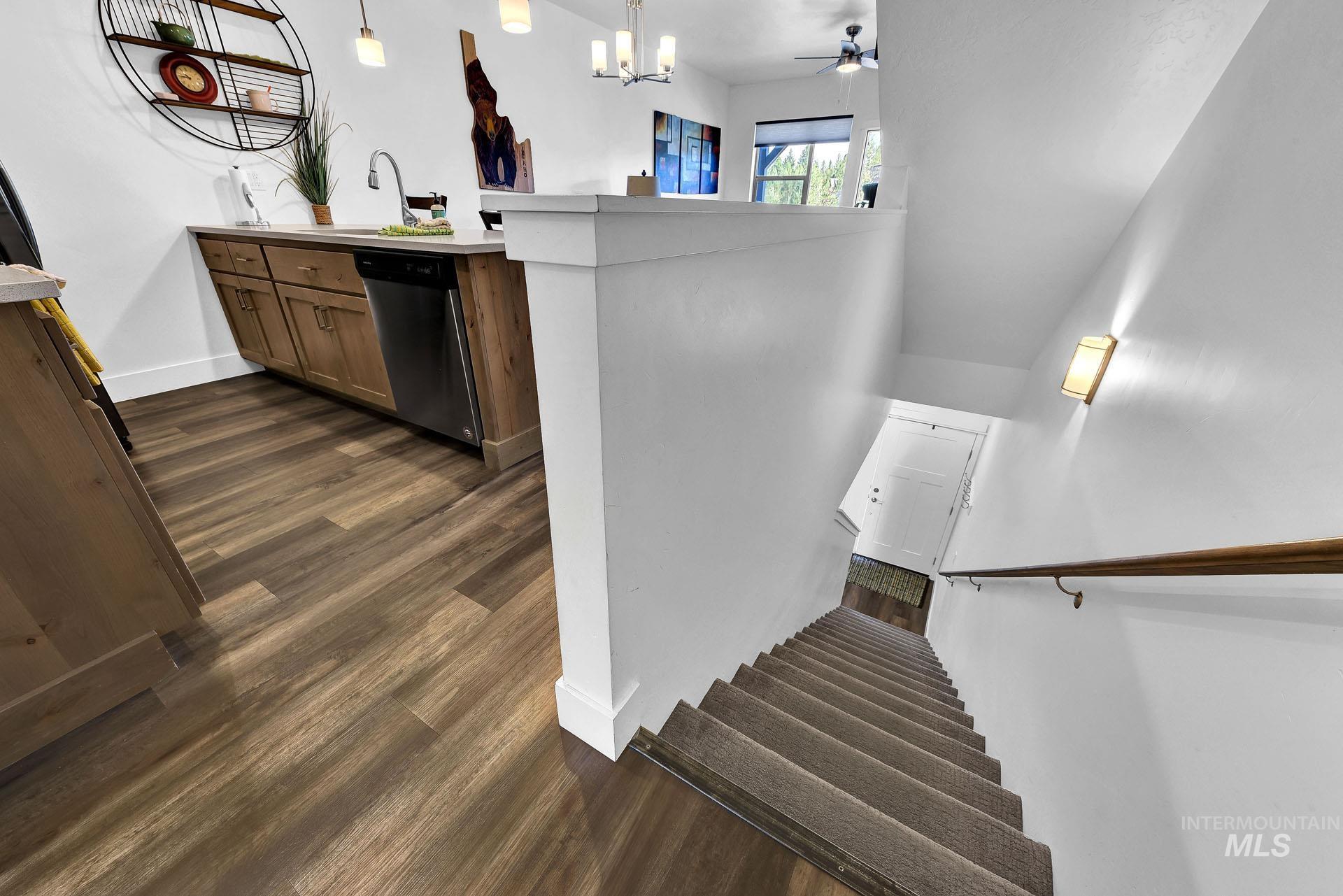 Staircase featuring wood finished floors, ceiling fan, and suspended lighting