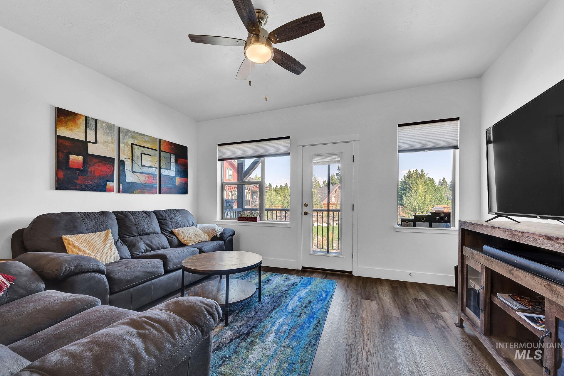 Living area with ceiling fan and dark wood-style floors