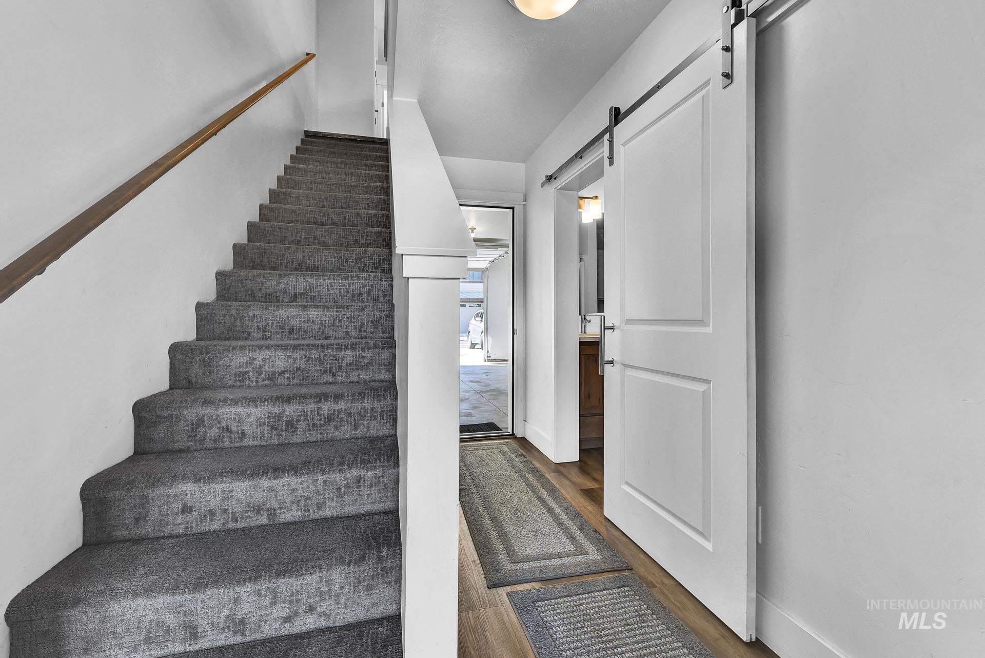 Stairway with a barn door and wood finished floors