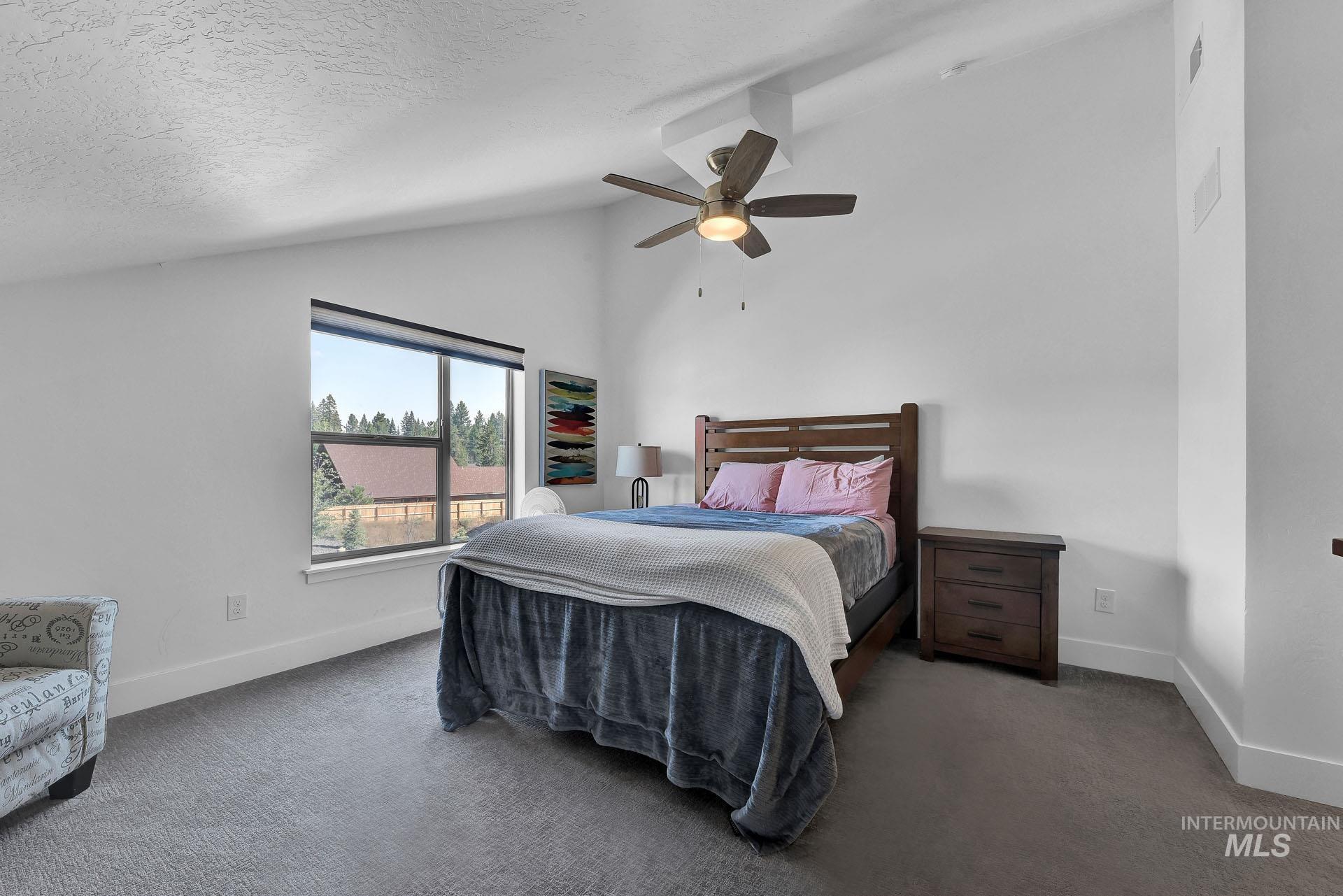 Bedroom featuring dark carpet, a ceiling fan, and a high textured ceiling