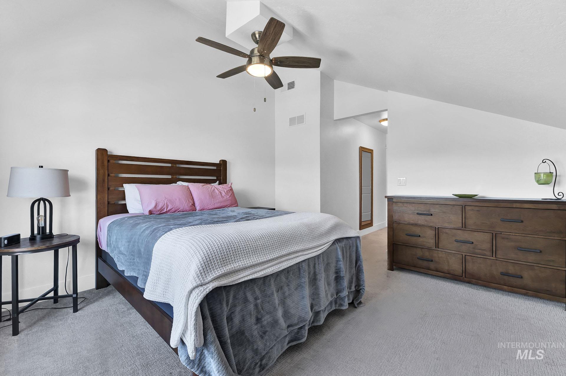 Bedroom with lofted ceiling, light carpet, and ceiling fan