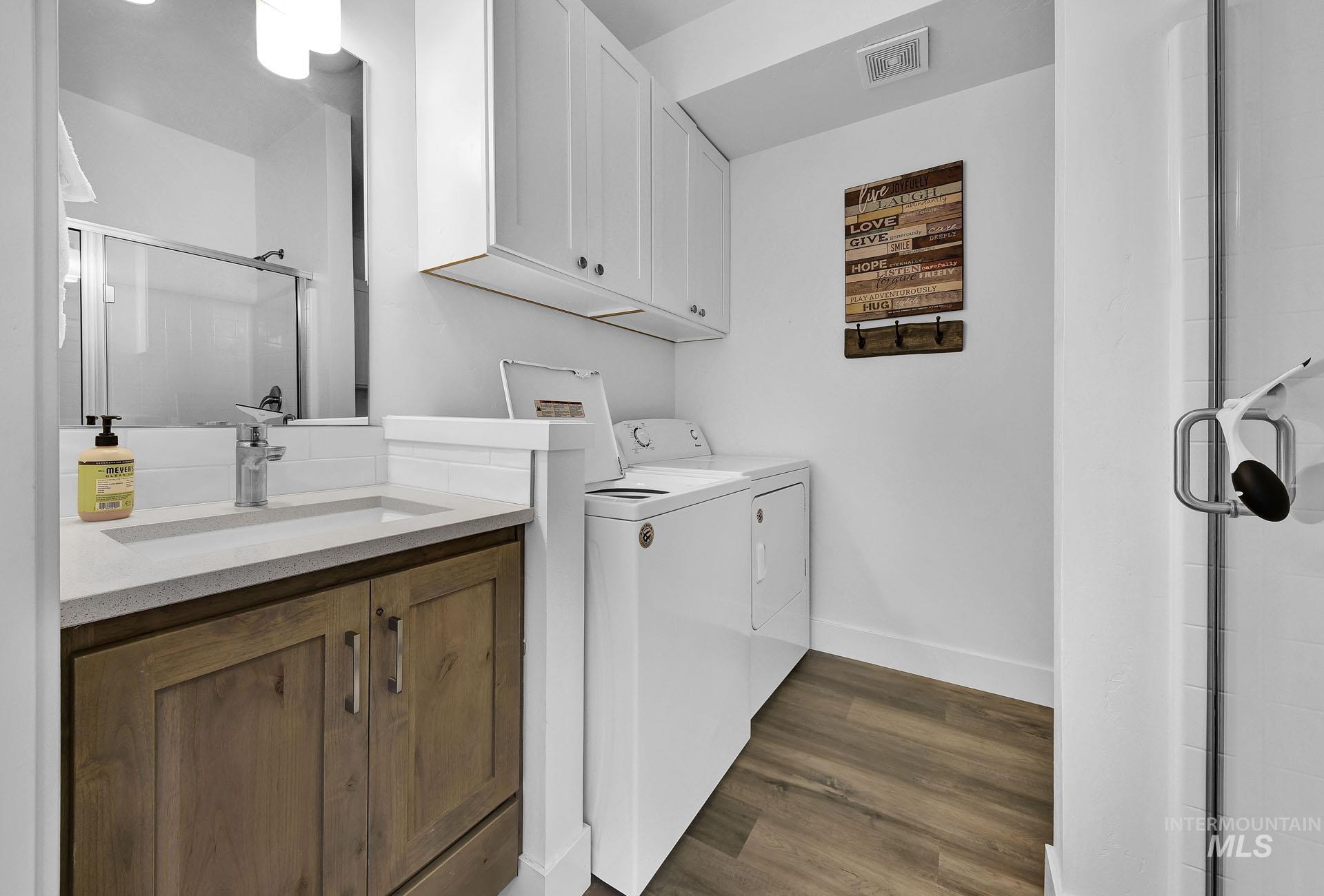 Laundry room with dark wood finished floors and washing machine and clothes dryer
