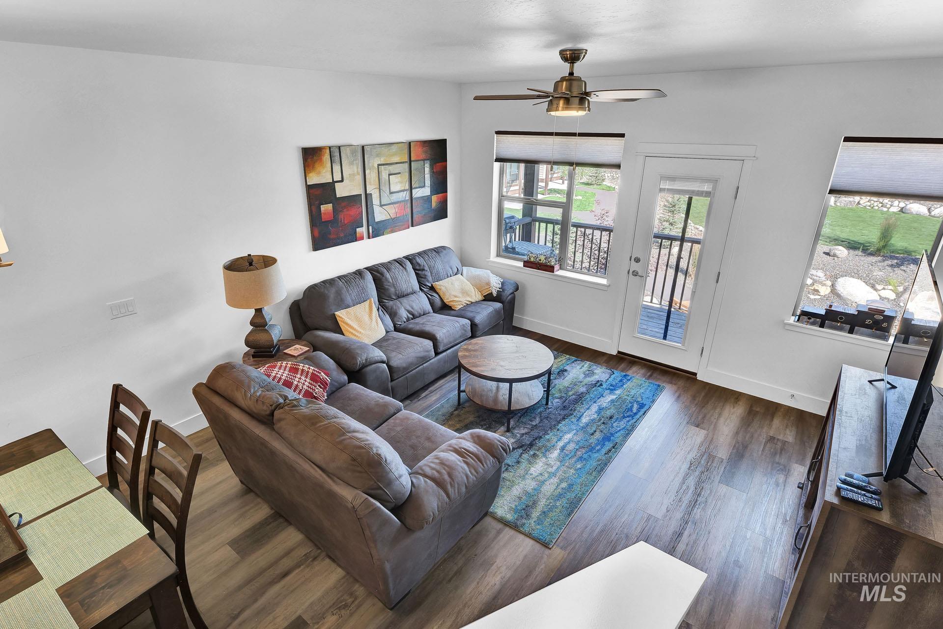 Living area featuring a ceiling fan and dark wood-type flooring