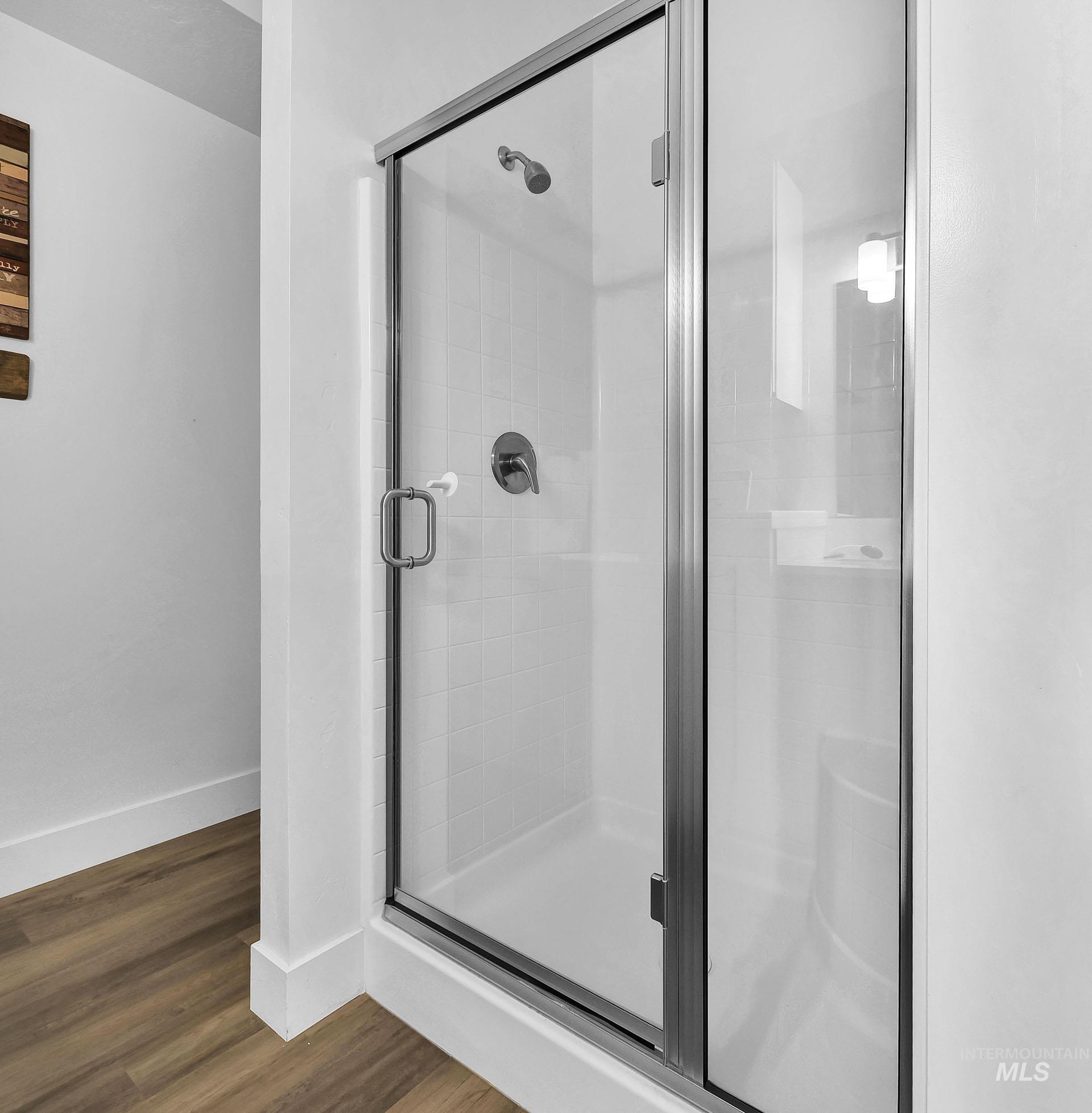 Full bathroom featuring a stall shower and dark wood-type flooring