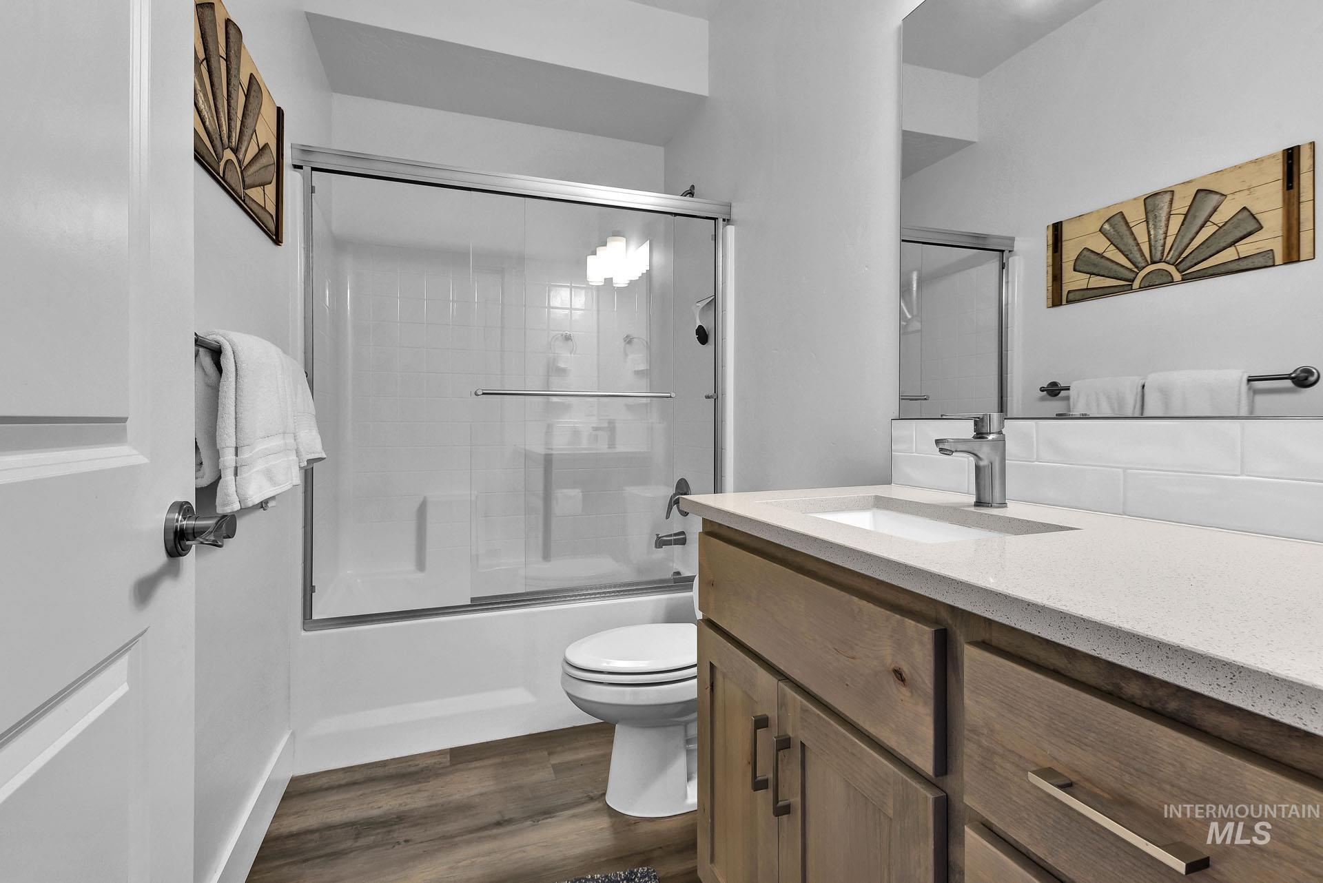 Bathroom with vanity, dark wood finished floors, and bath / shower combo with glass door