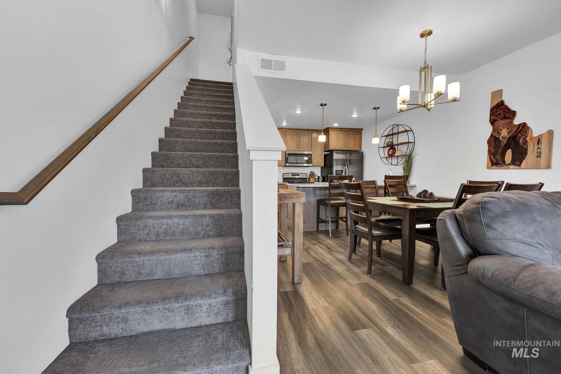 Staircase featuring wood finished floors and hanging lights