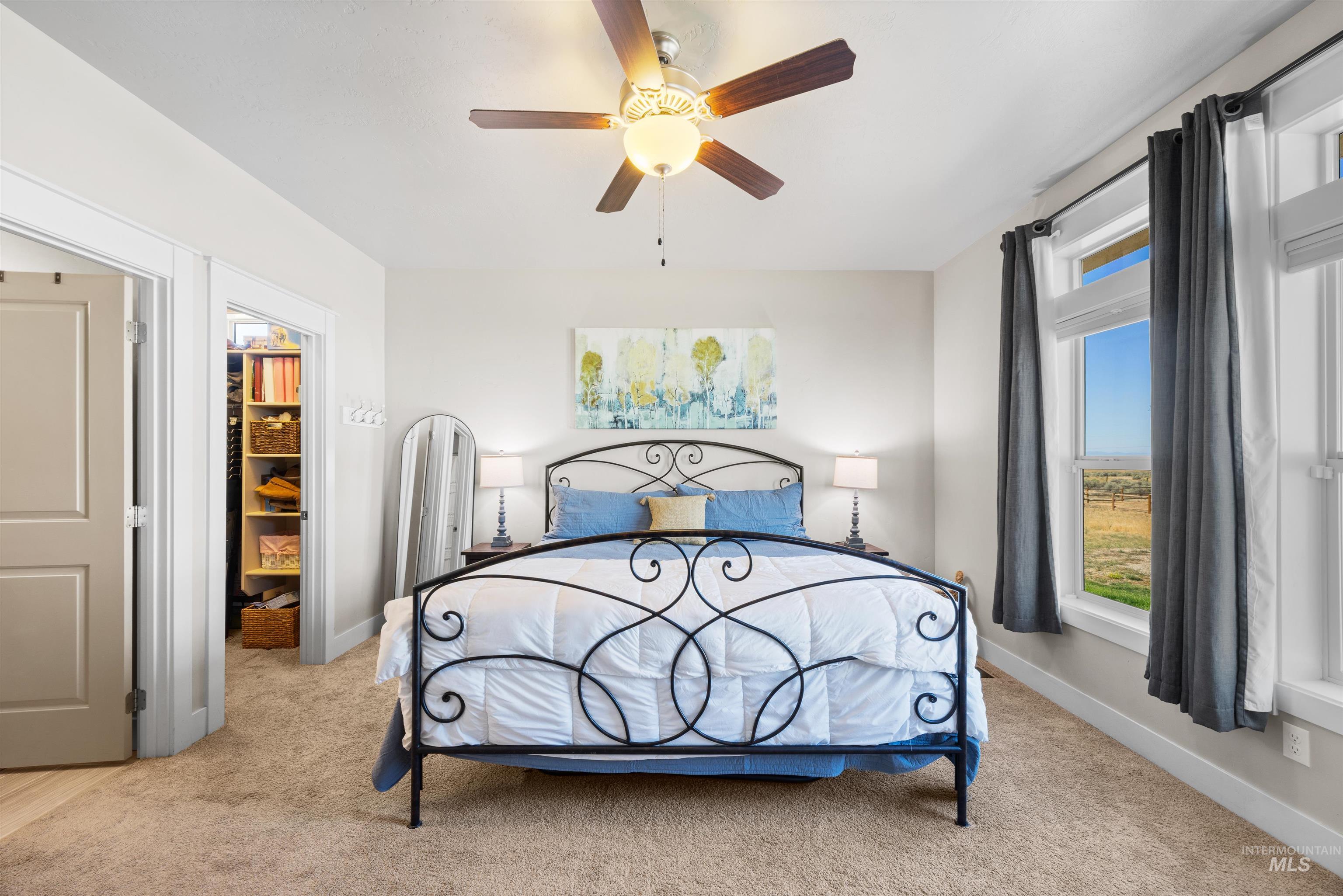 Bedroom with light colored carpet, a ceiling fan, and a spacious closet