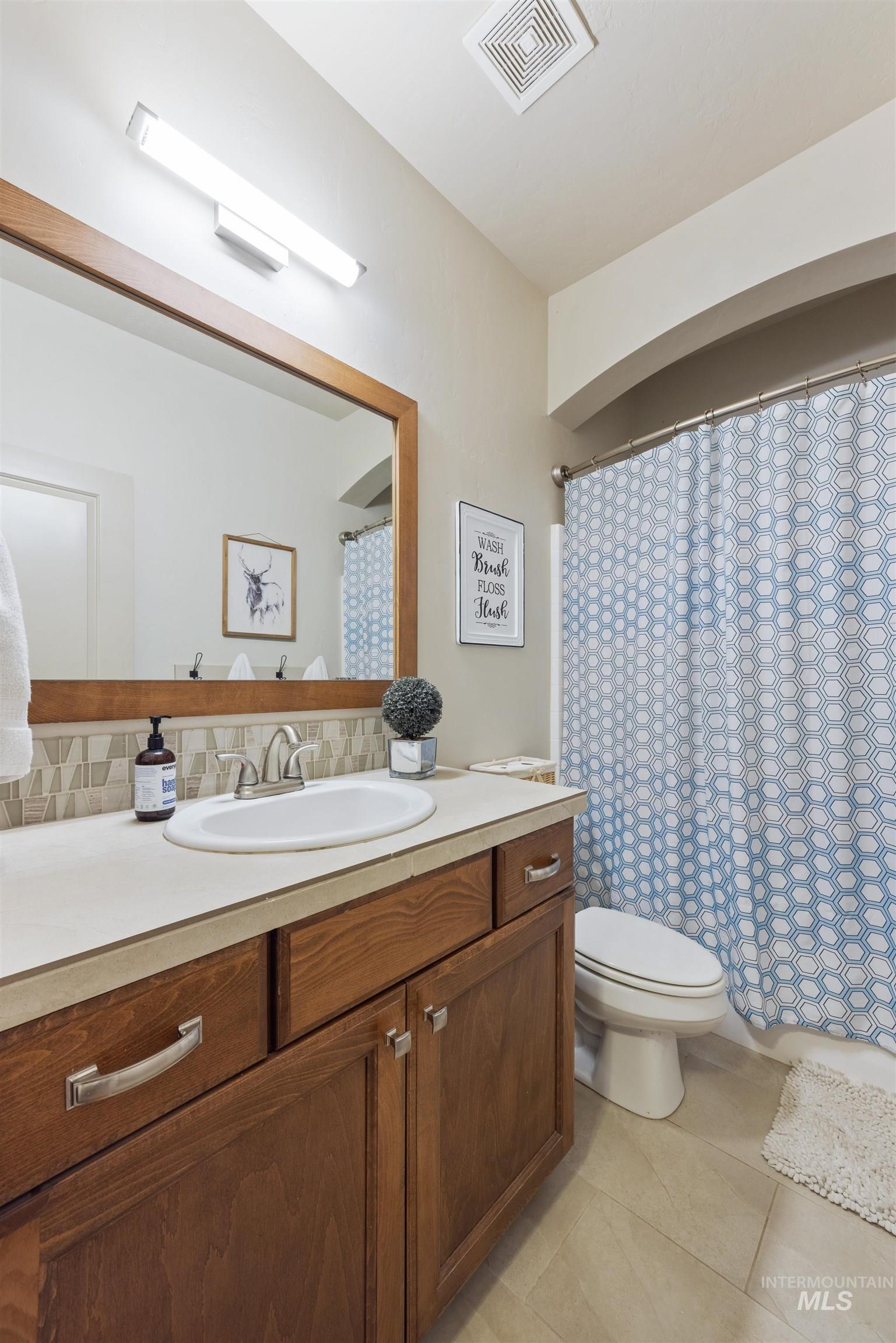Bathroom with vanity, light tile patterned flooring, tasteful backsplash, and curtained shower