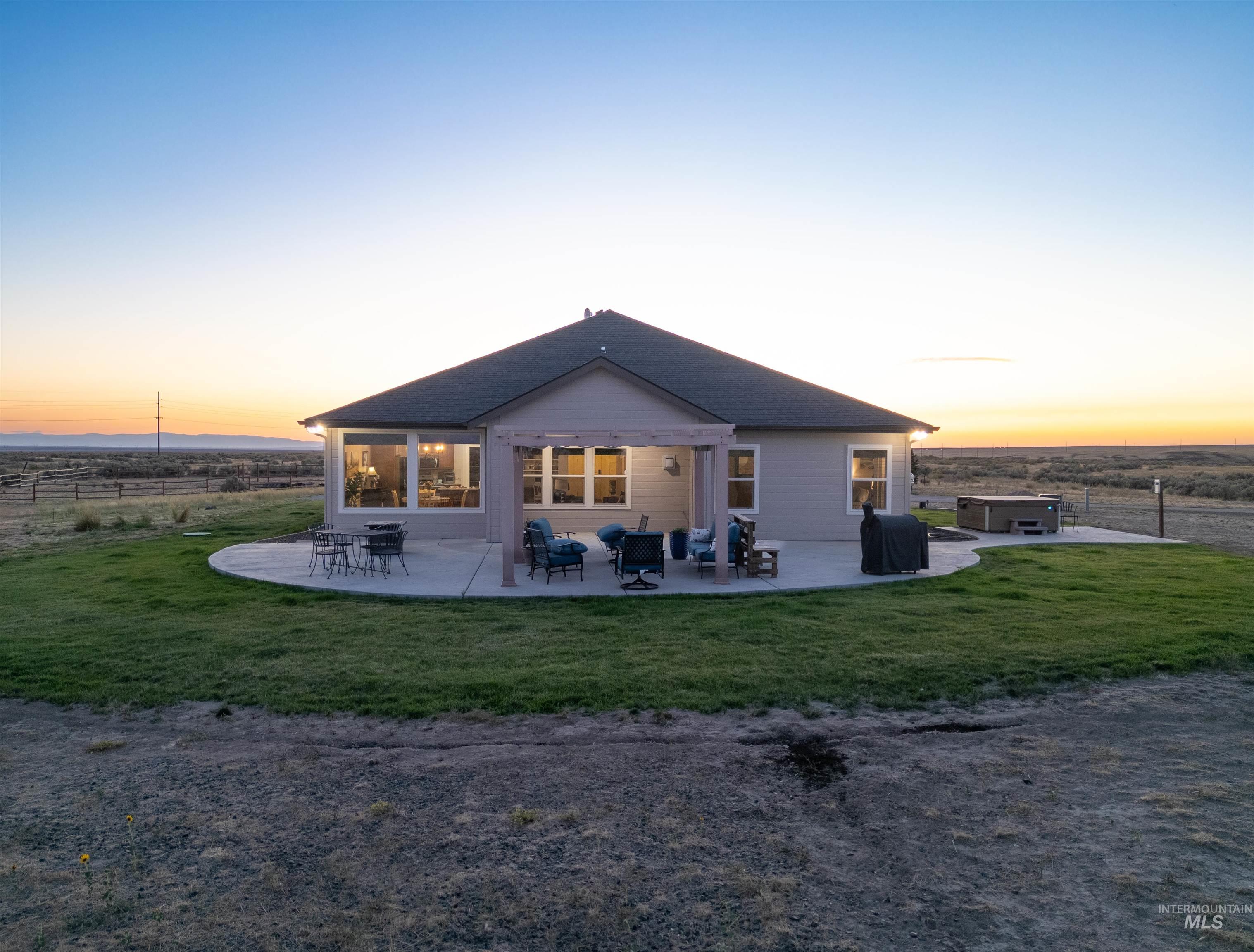 Back of property at dusk featuring a patio area and a lawn