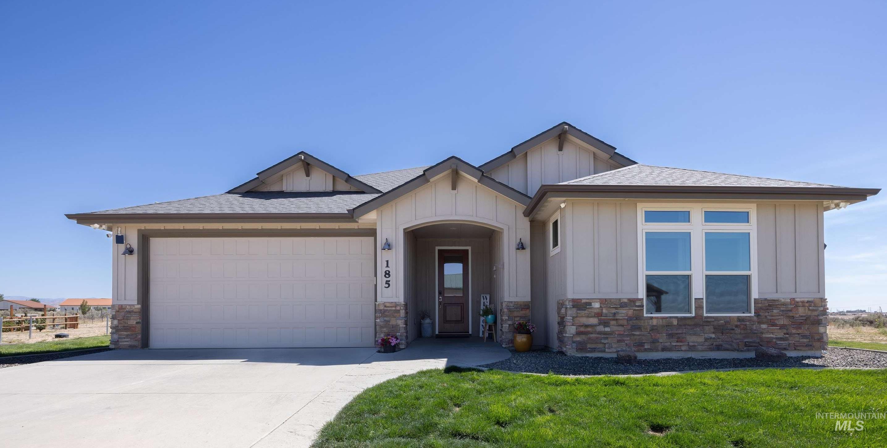 View of front of house with concrete driveway, board and batten siding, stone siding, and a shingled roof