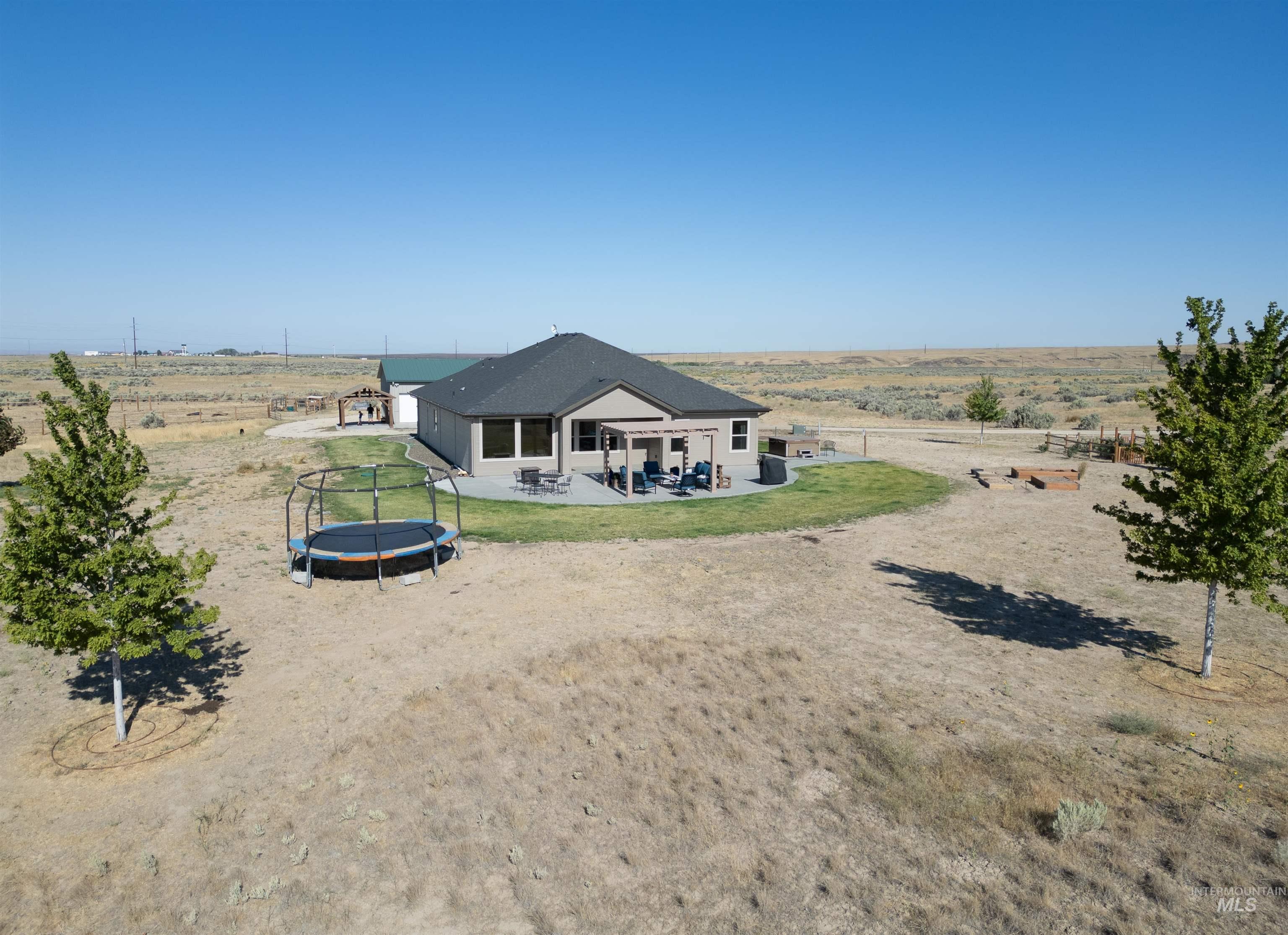 Back of house featuring a trampoline, a patio, and a view of countryside