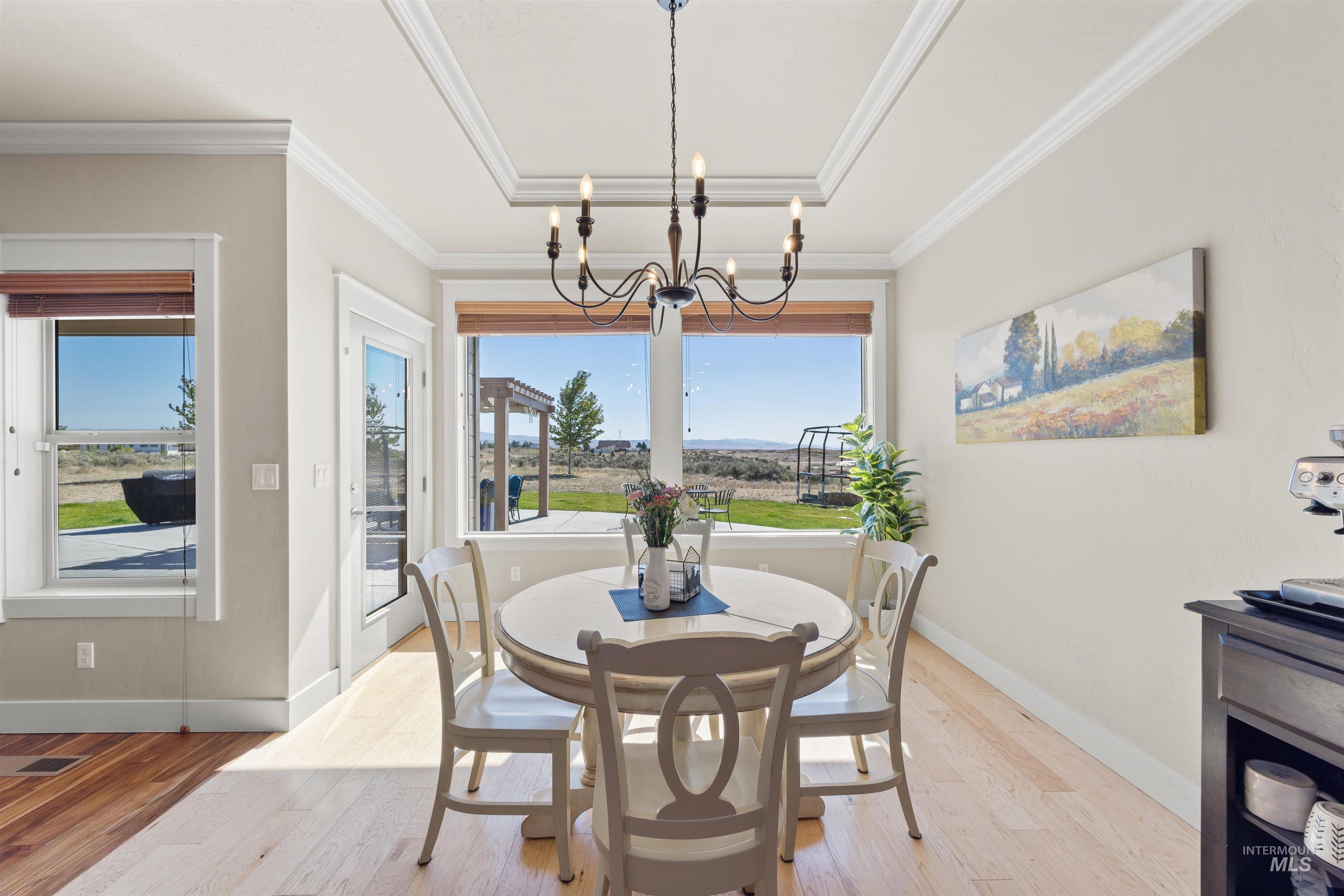 Dining room with light wood-style flooring, ornamental molding, and a chandelier