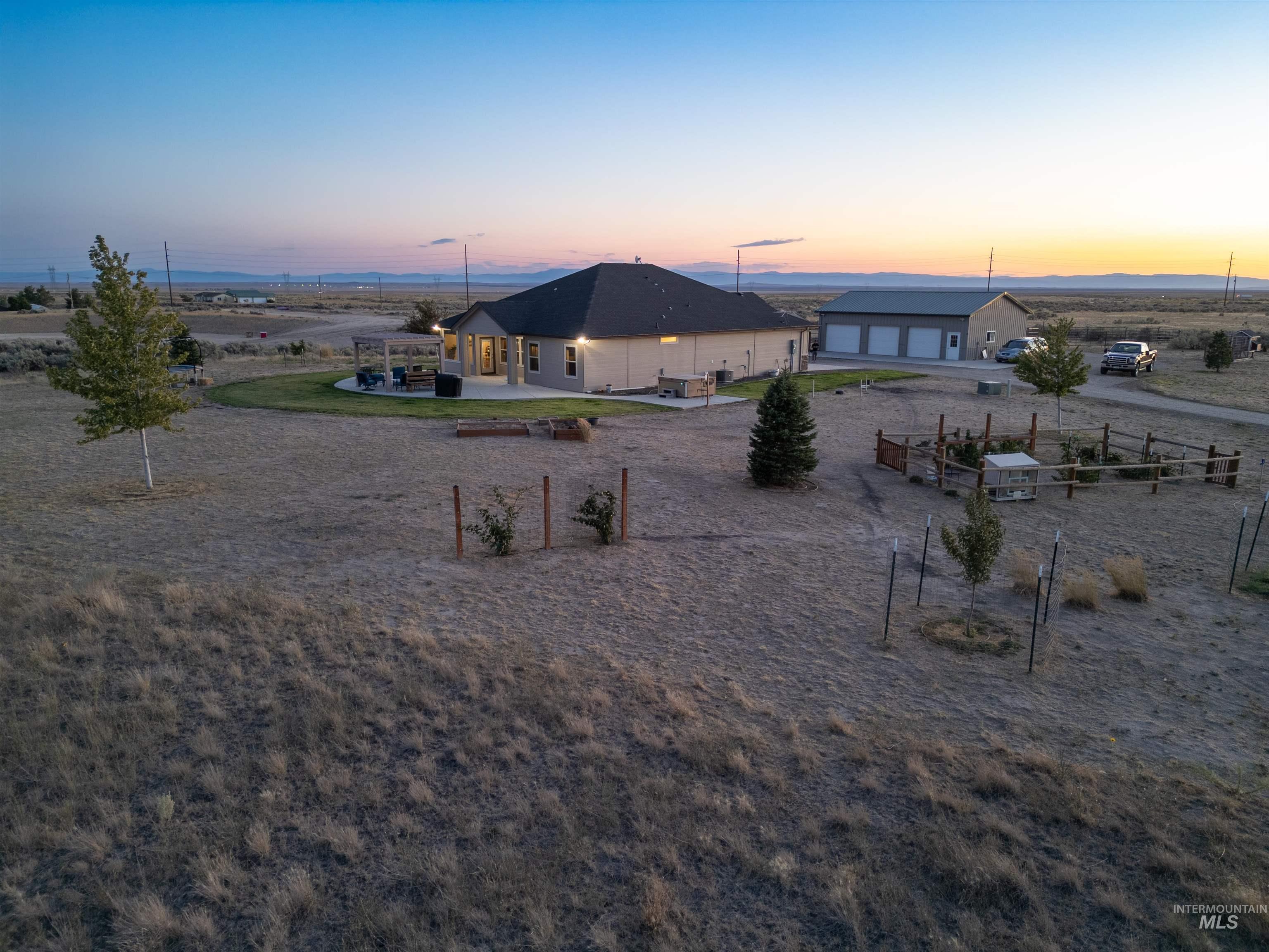 Yard at dusk with a patio area, driveway, and a detached garage