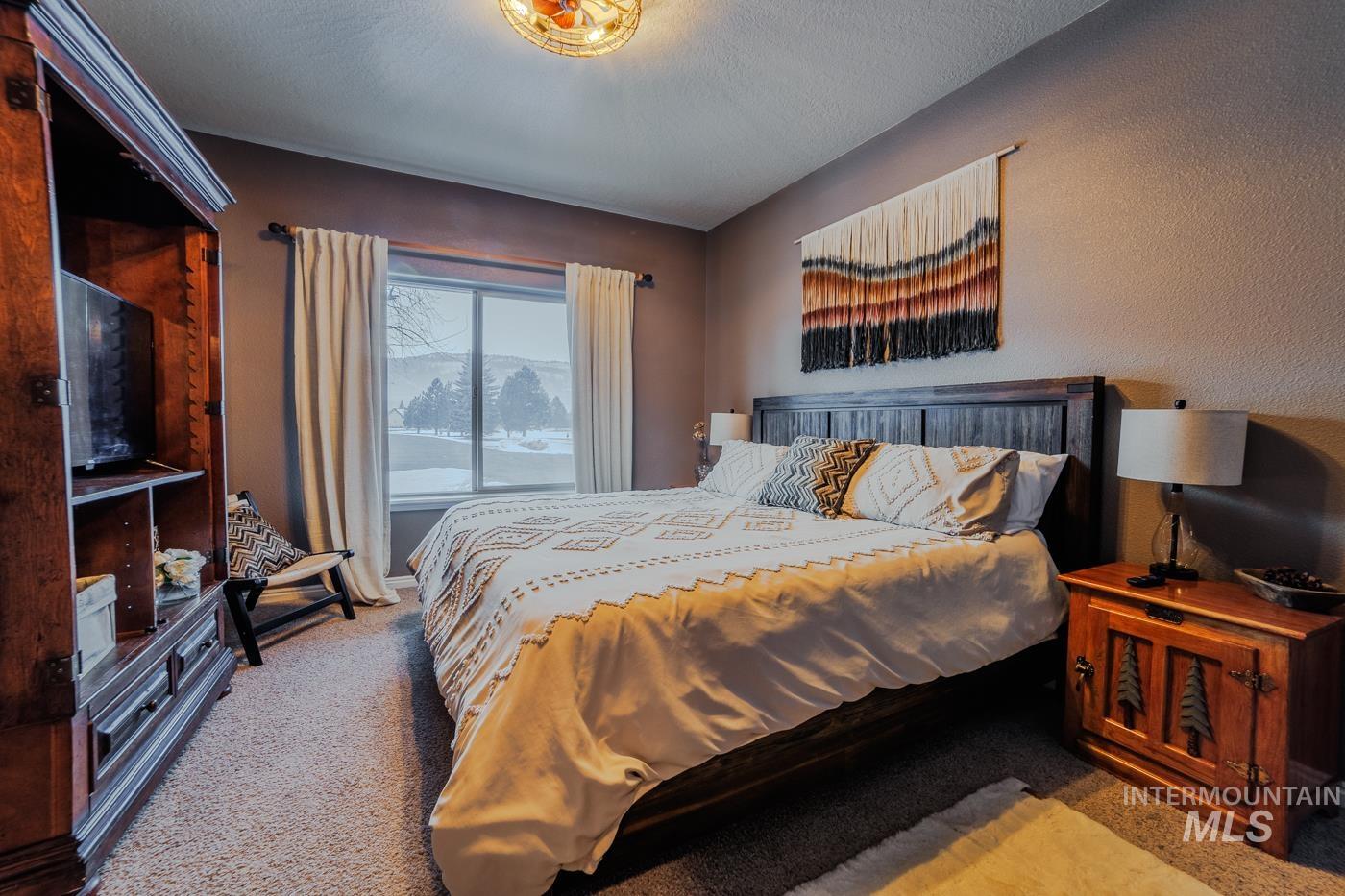 Carpeted bedroom featuring a textured ceiling and a textured wall