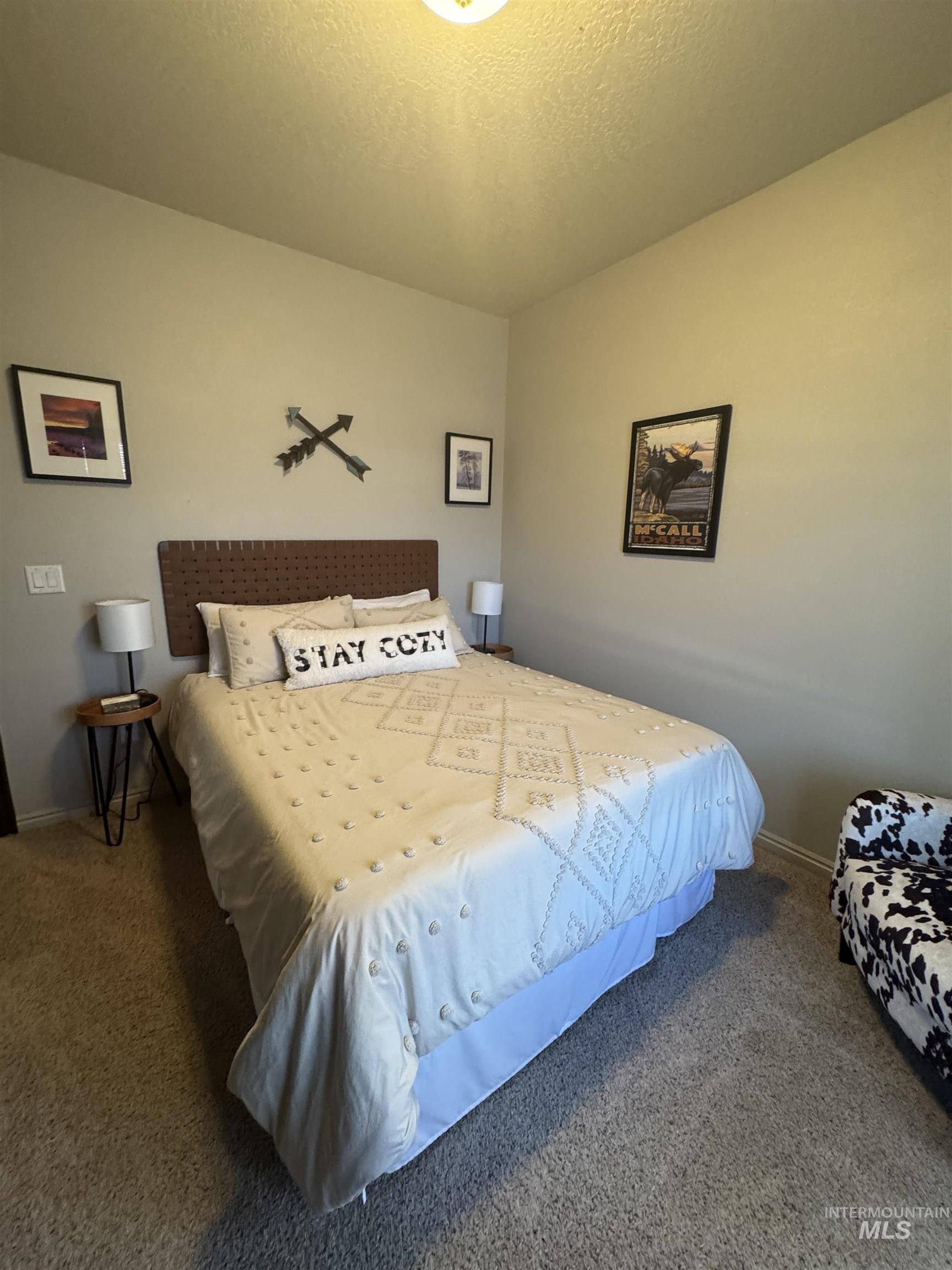 Bedroom featuring dark carpet and a textured ceiling