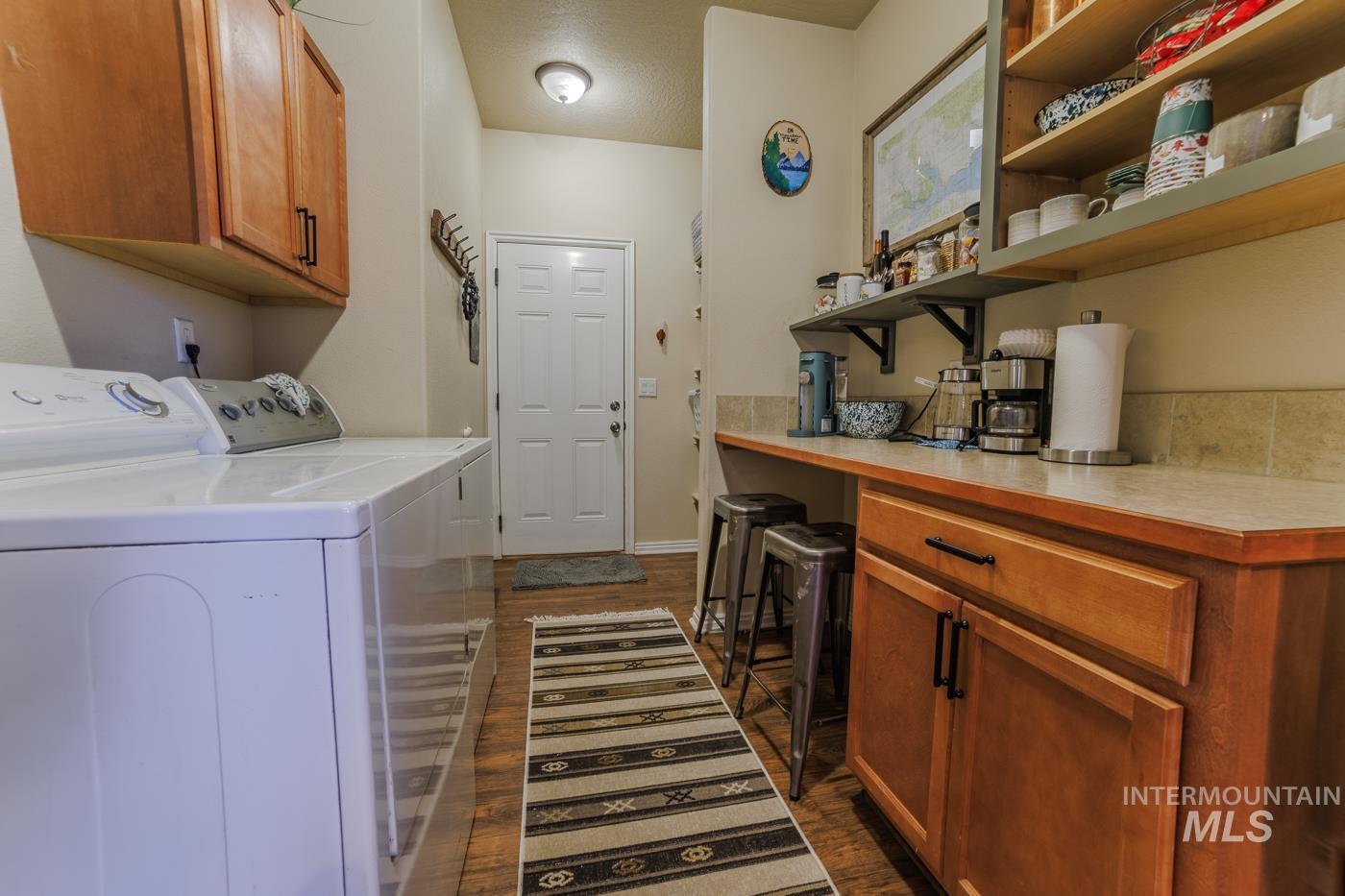 Laundry room with cabinet space, dark wood finished floors, and washing machine and clothes dryer