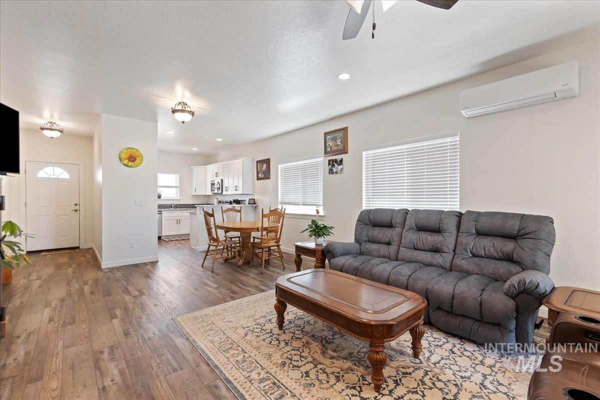 Living area with recessed lighting, a wall unit AC, dark wood-style flooring, and a ceiling fan