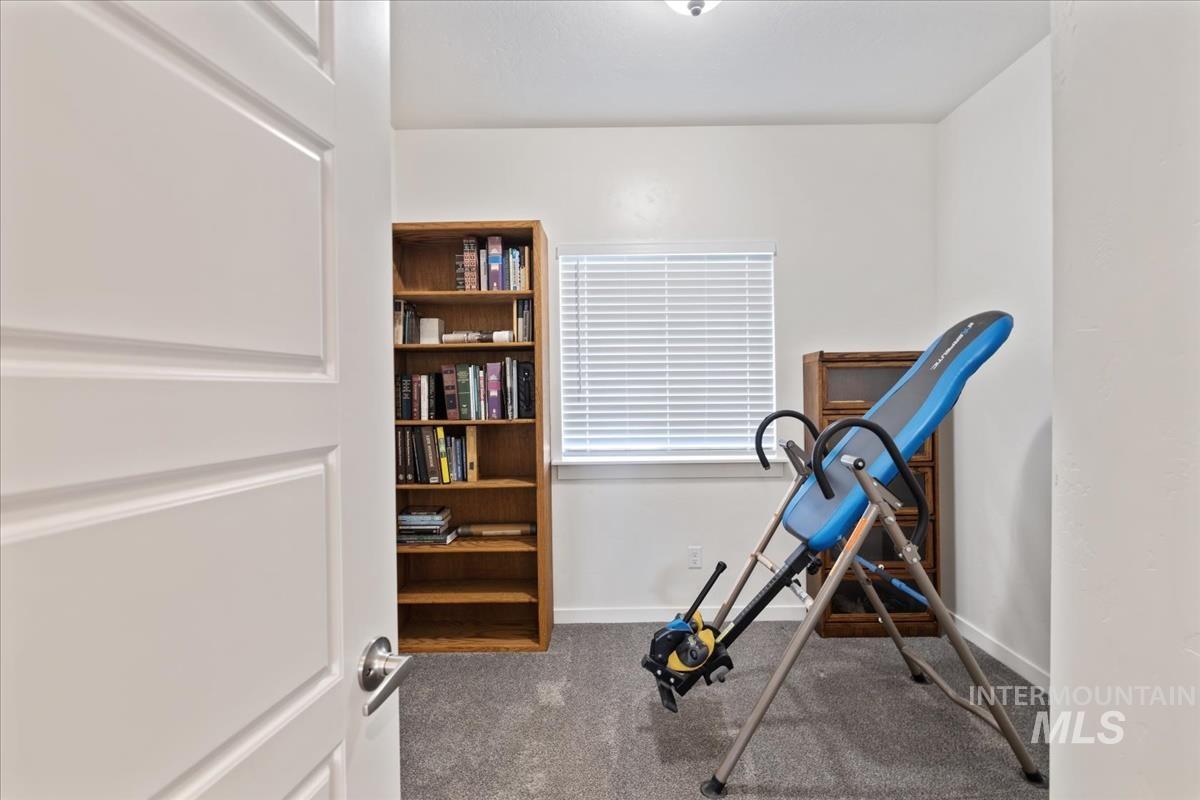 Workout room with dark carpet and baseboards