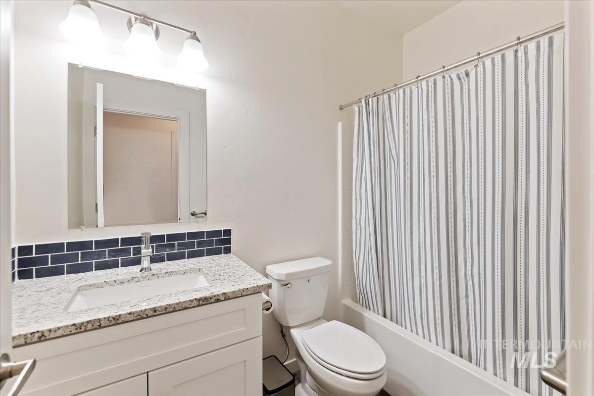 Full bathroom featuring tasteful backsplash, shower / bath combo, and vanity