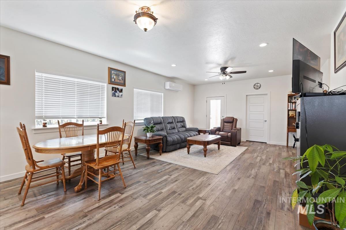 Dining room with recessed lighting, light wood-style floors, ceiling fan, and a wall mounted air conditioner