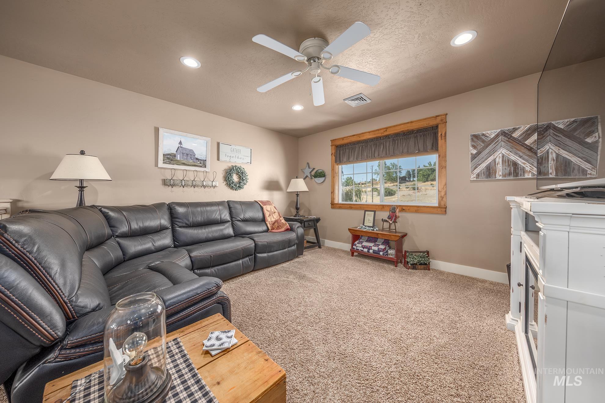 Carpeted room featuring a ceiling fan, recessed lighting, and a window with wood trim