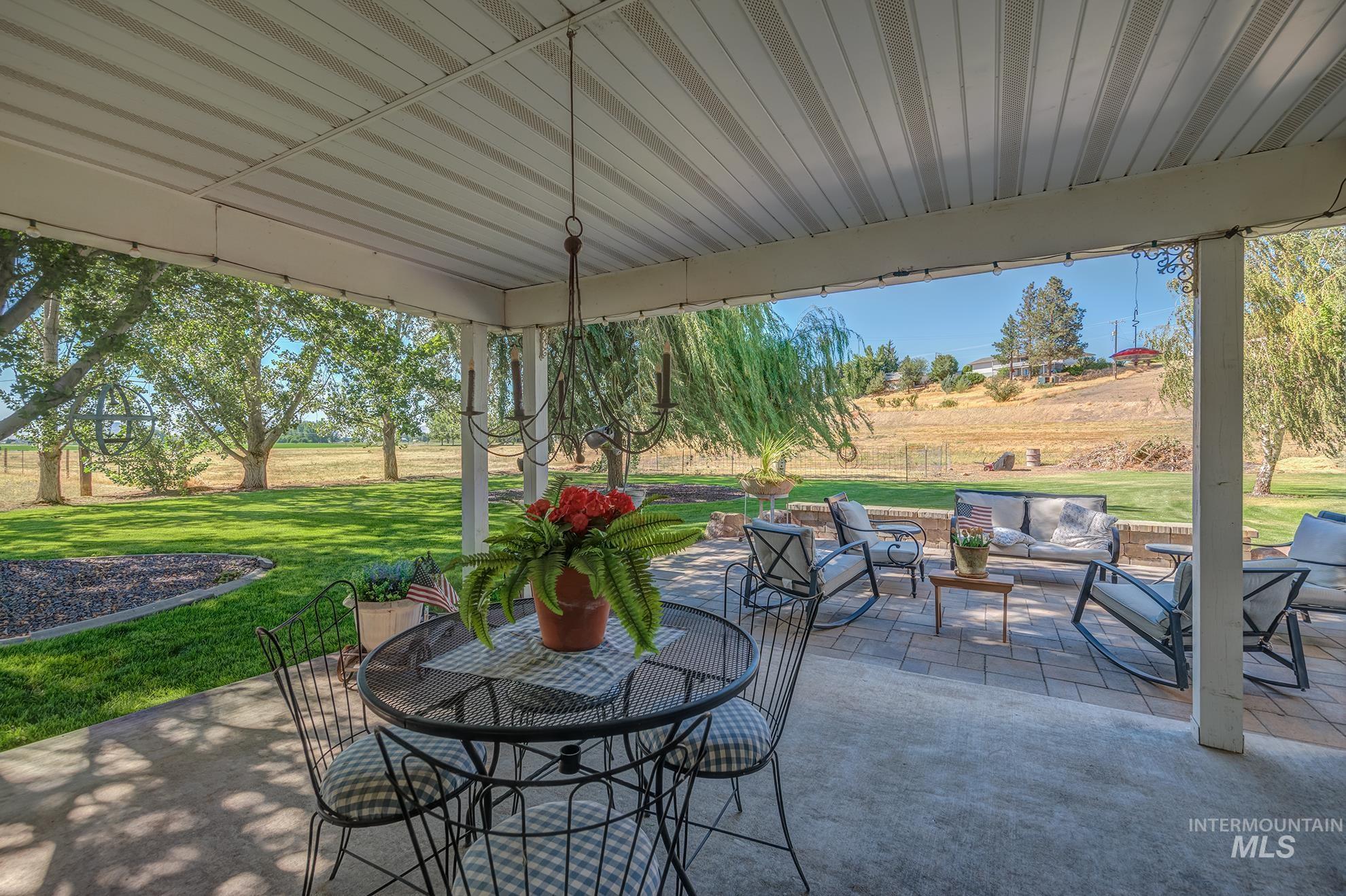 Covered patio featuring a metal chandelier, concrete flooring, and an additional paver patio area