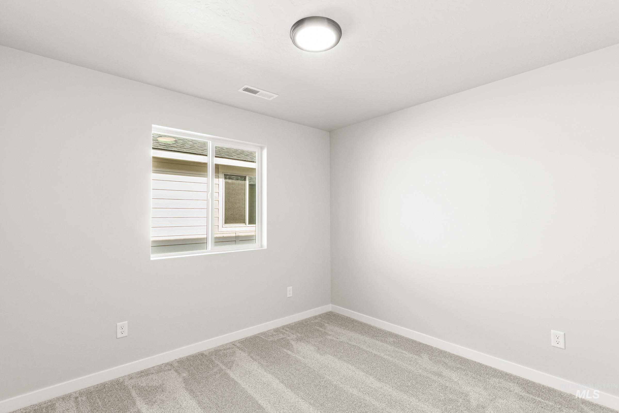 Carpeted spare room featuring baseboards