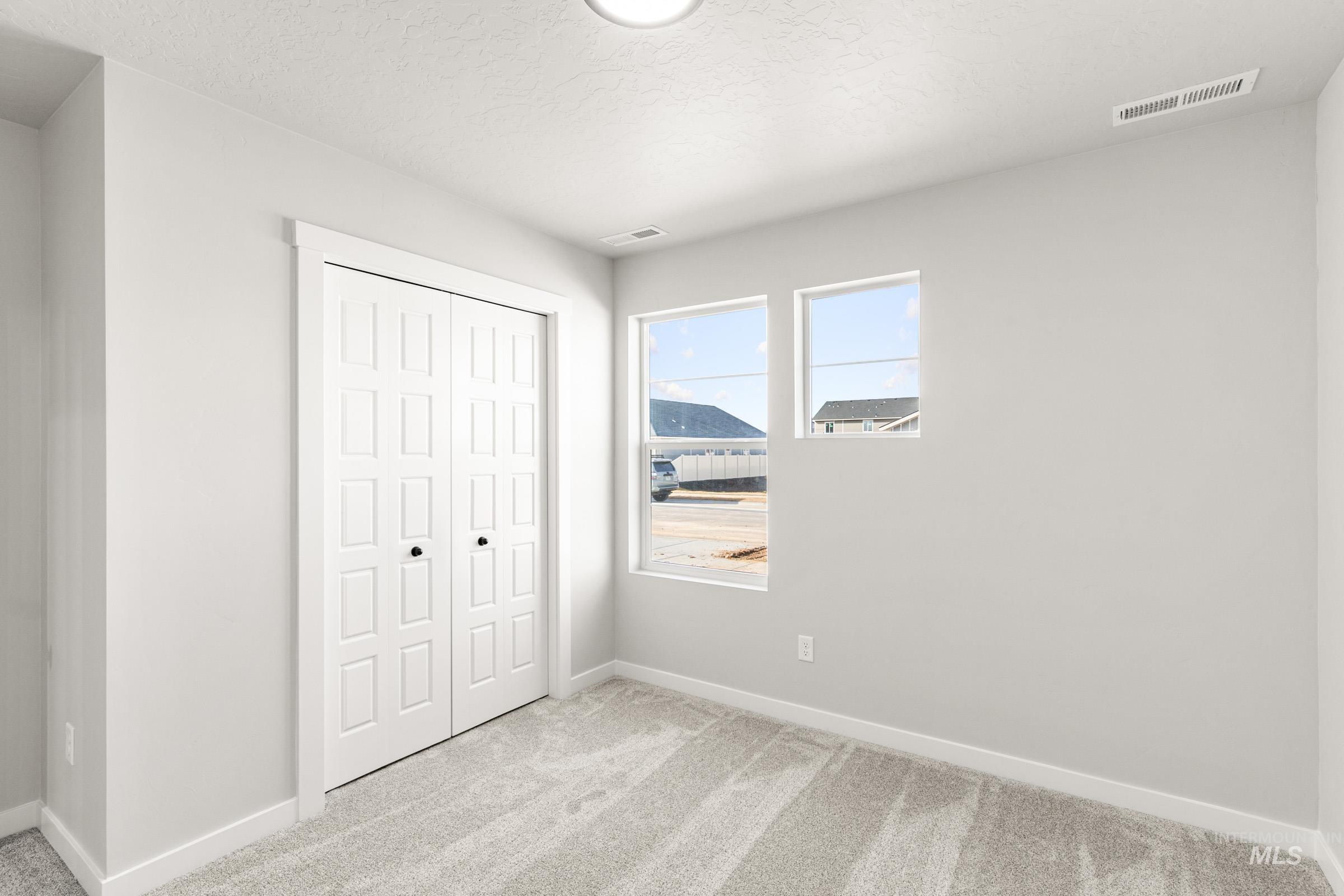 Unfurnished bedroom featuring light colored carpet, a closet, and a textured ceiling