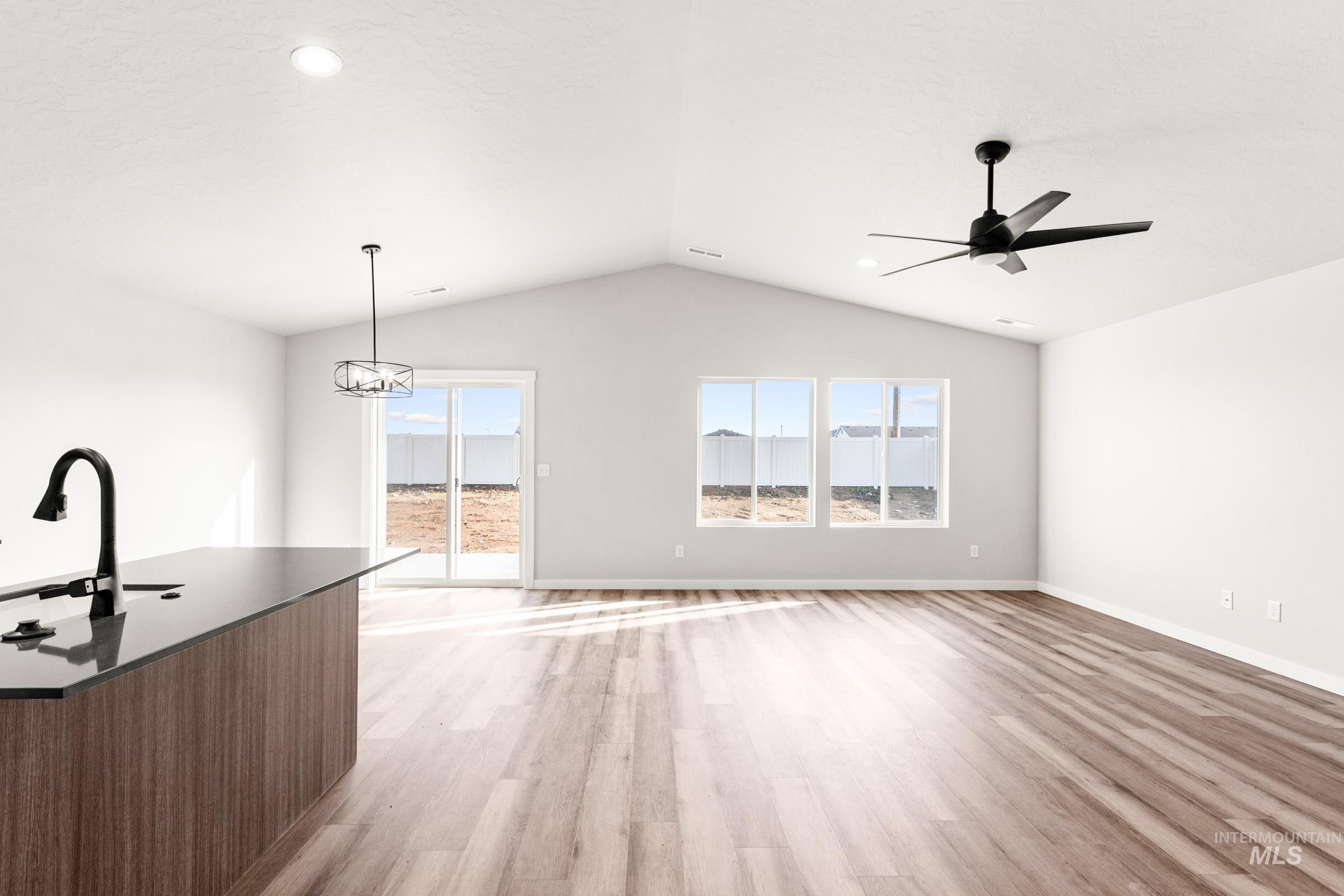 Unfurnished living room featuring light wood-type flooring, ceiling fan, and suspended lighting