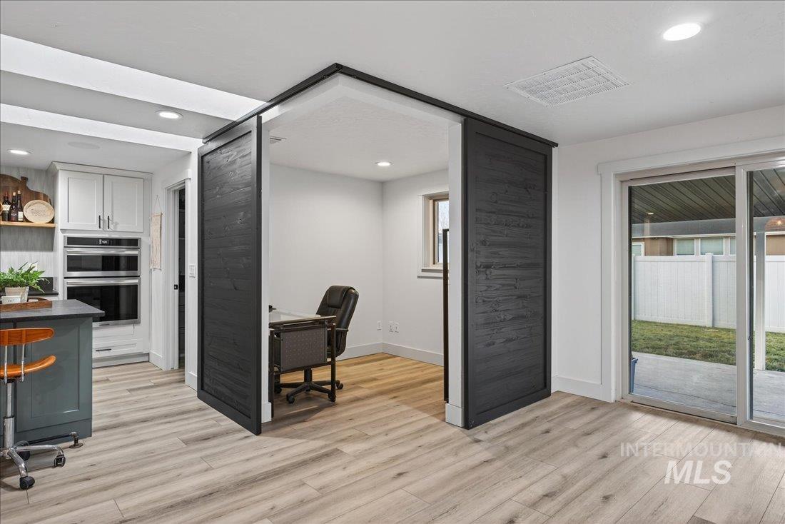 Home office with light wood-type flooring and recessed lighting