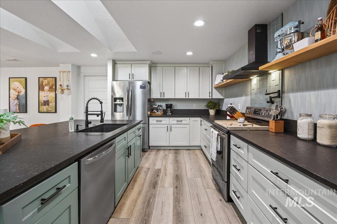 Kitchen featuring appliances with stainless steel finishes, open shelves, recessed lighting, wall chimney exhaust hood, and white cabinetry