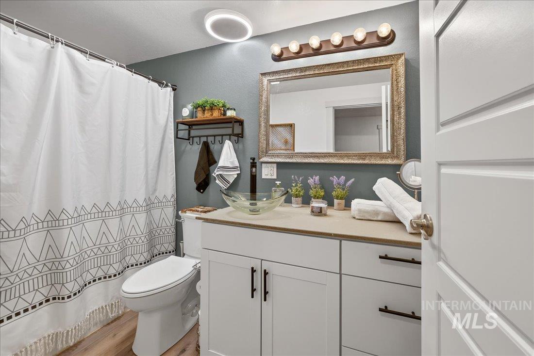 Bathroom with vanity, a shower with curtain, and light wood-style floors