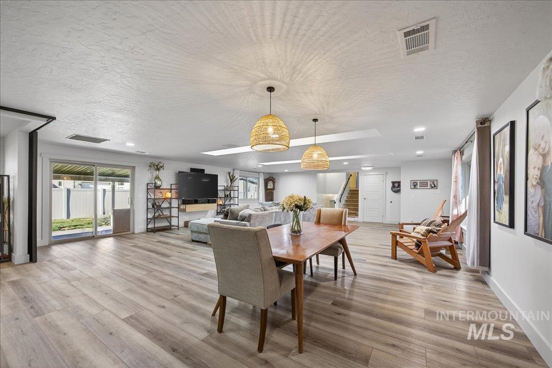 Dining space with a textured ceiling, recessed lighting, light wood-style floors, healthy amount of natural light, and stairs