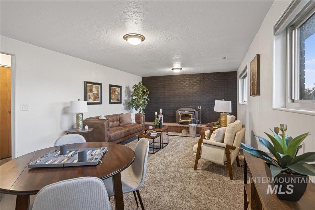 Carpeted living room featuring a wood stove, a textured ceiling, brick wall, and an accent wall