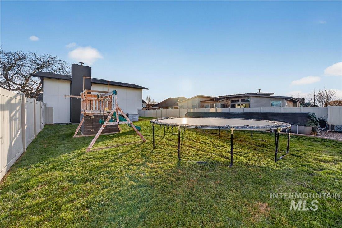 Fenced backyard with a trampoline and a playground